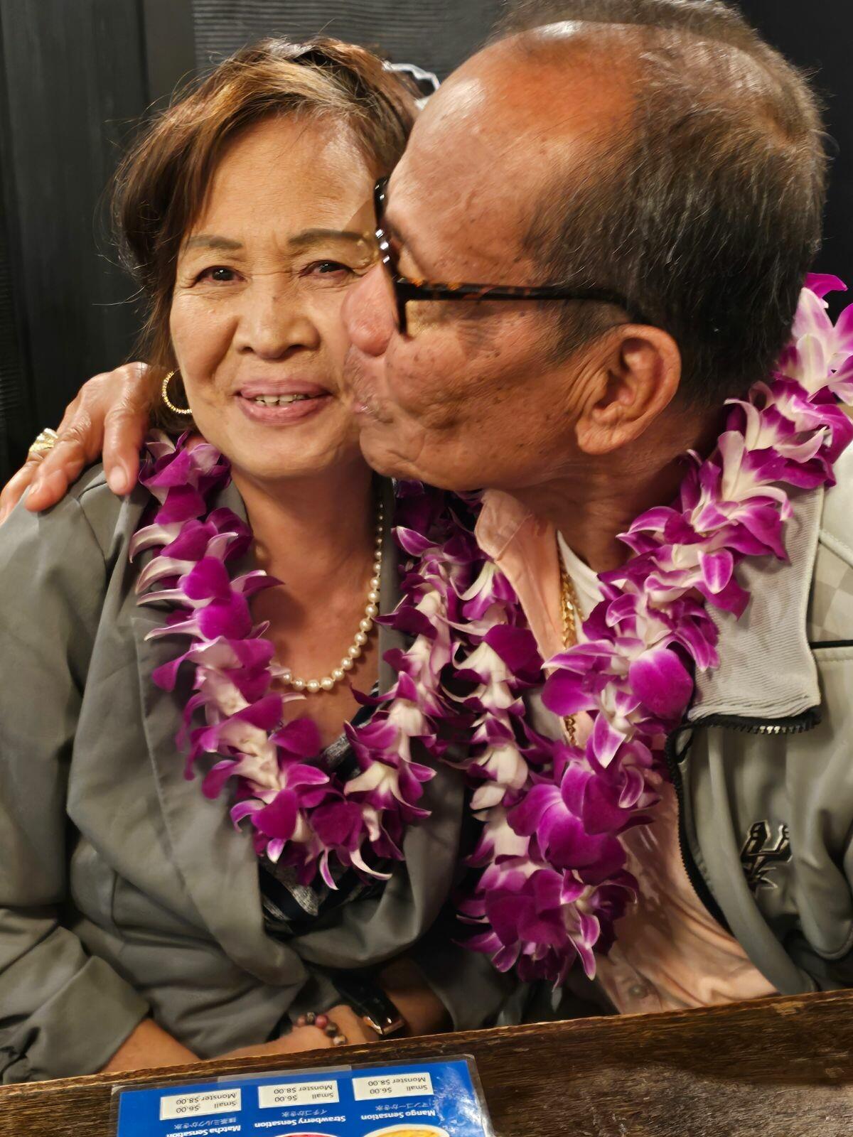 A man and woman wearing leis