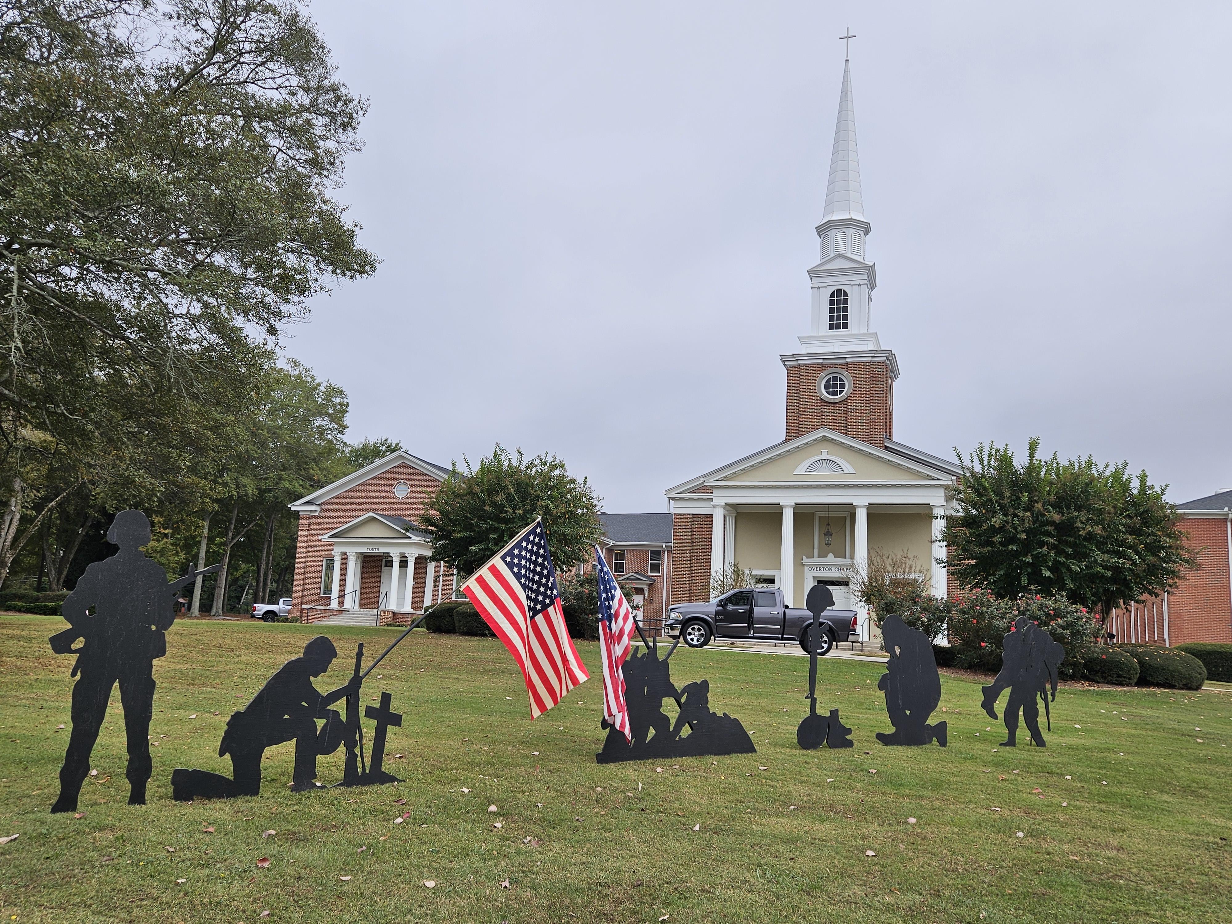 A group of black silhouettes of soldiers and flags in front of a church