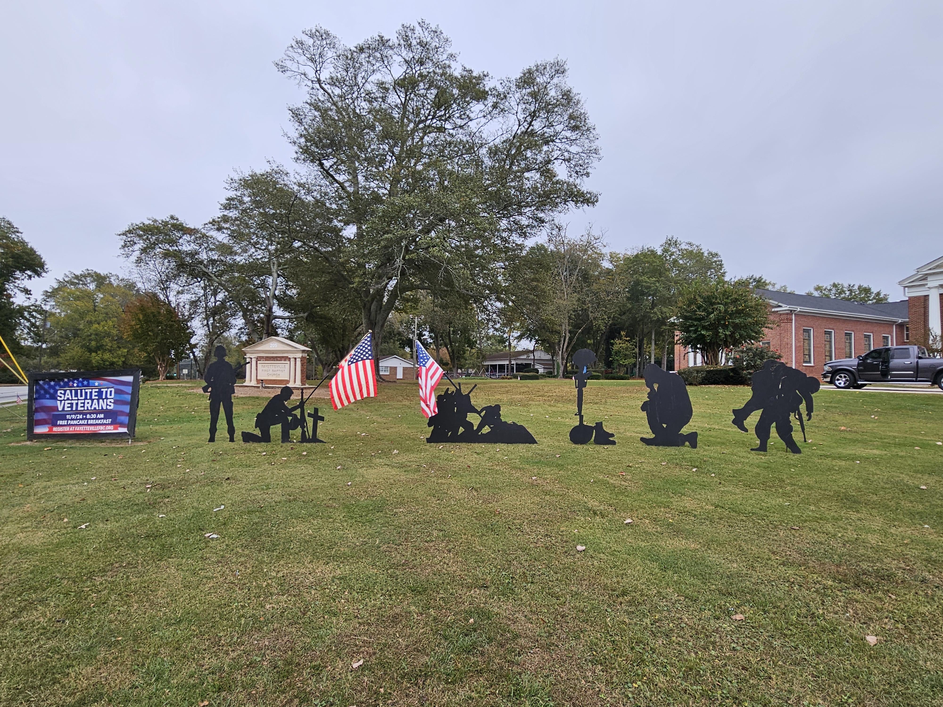A group of silhouettes of soldiers and flags in a grassy field