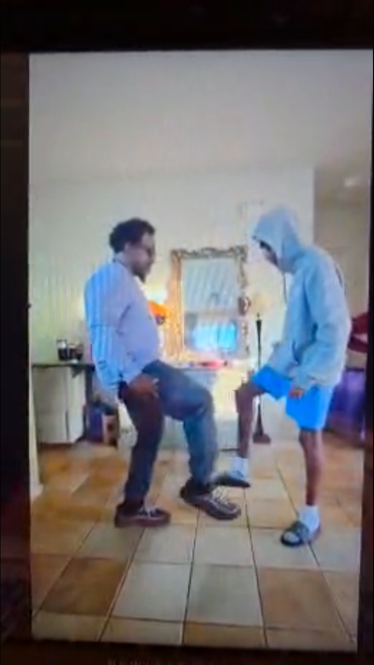 A man in a hoodie standing next to another man in a room