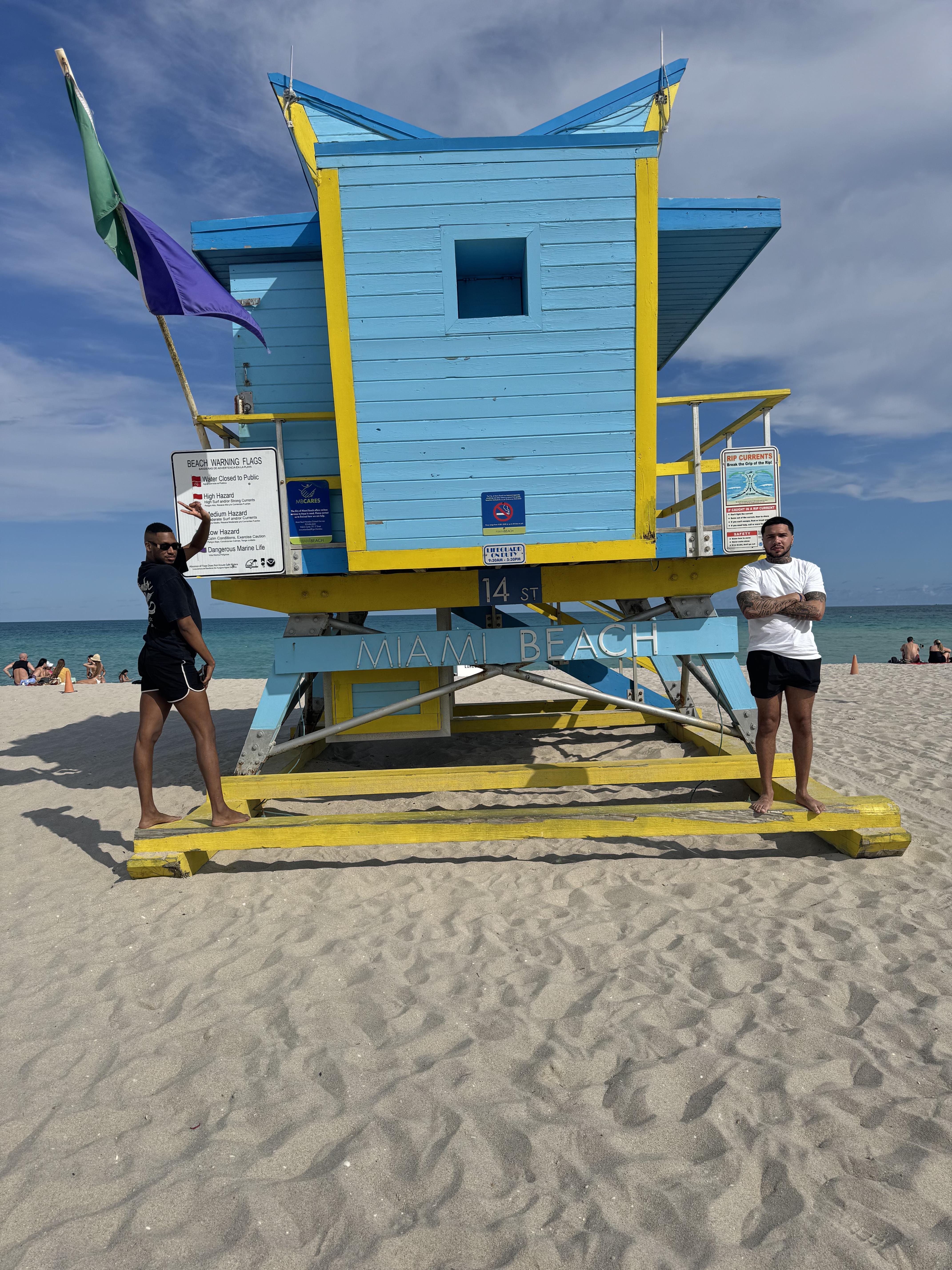 A couple of men standing on a lifeguard stand on a beach
