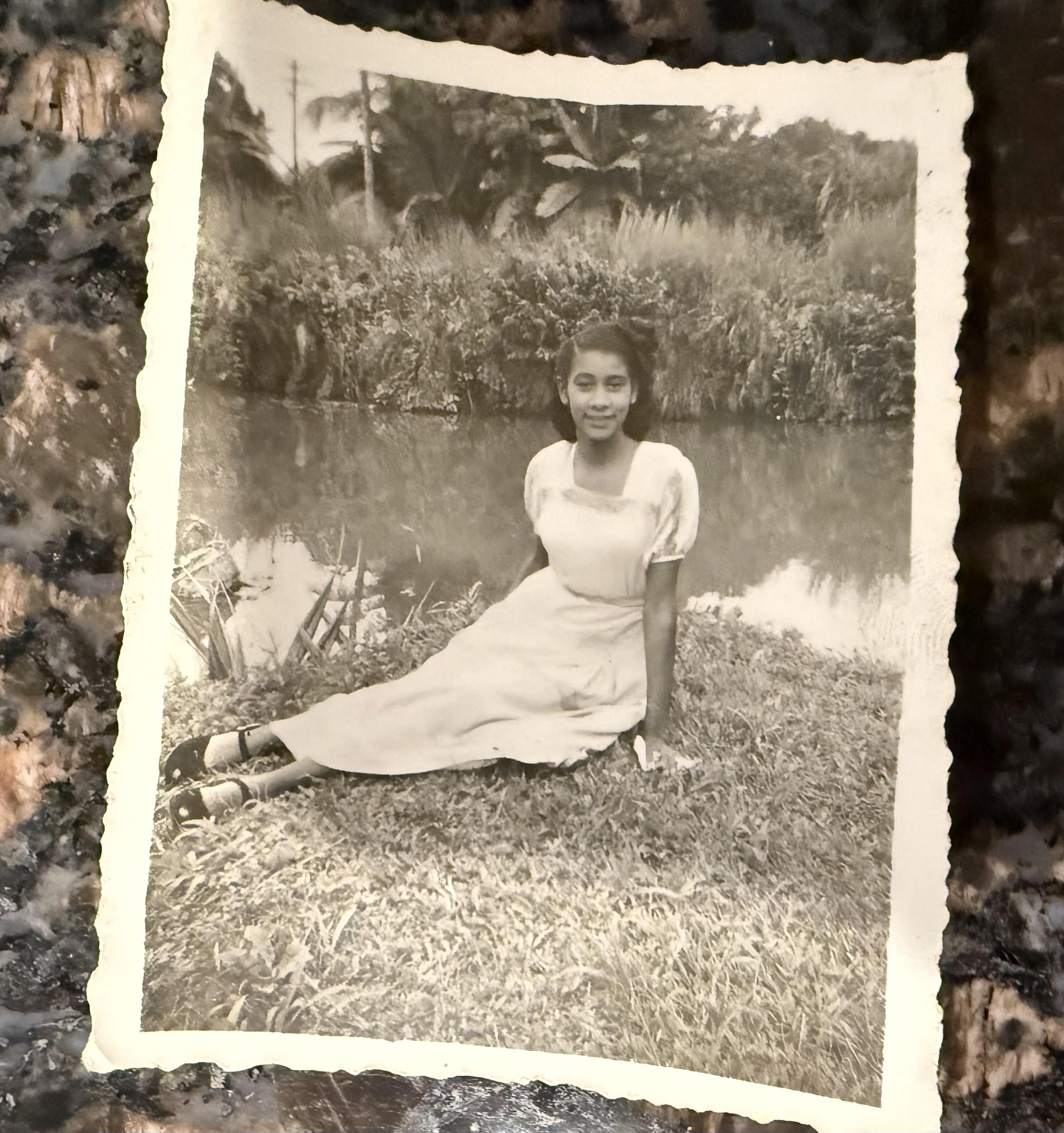 A woman sitting on grass near water