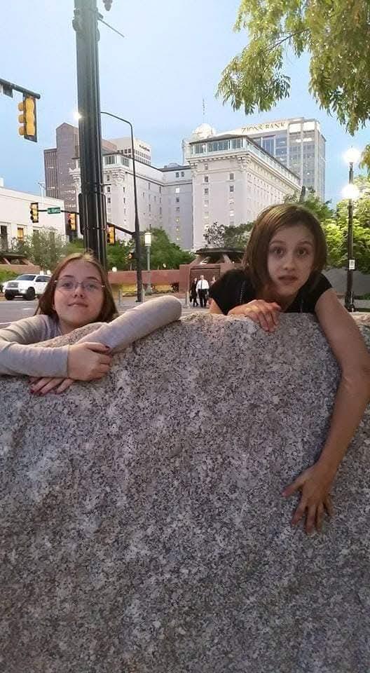 Two girls leaning on a rock