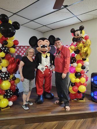 A group of people posing with a mickey mouse character
