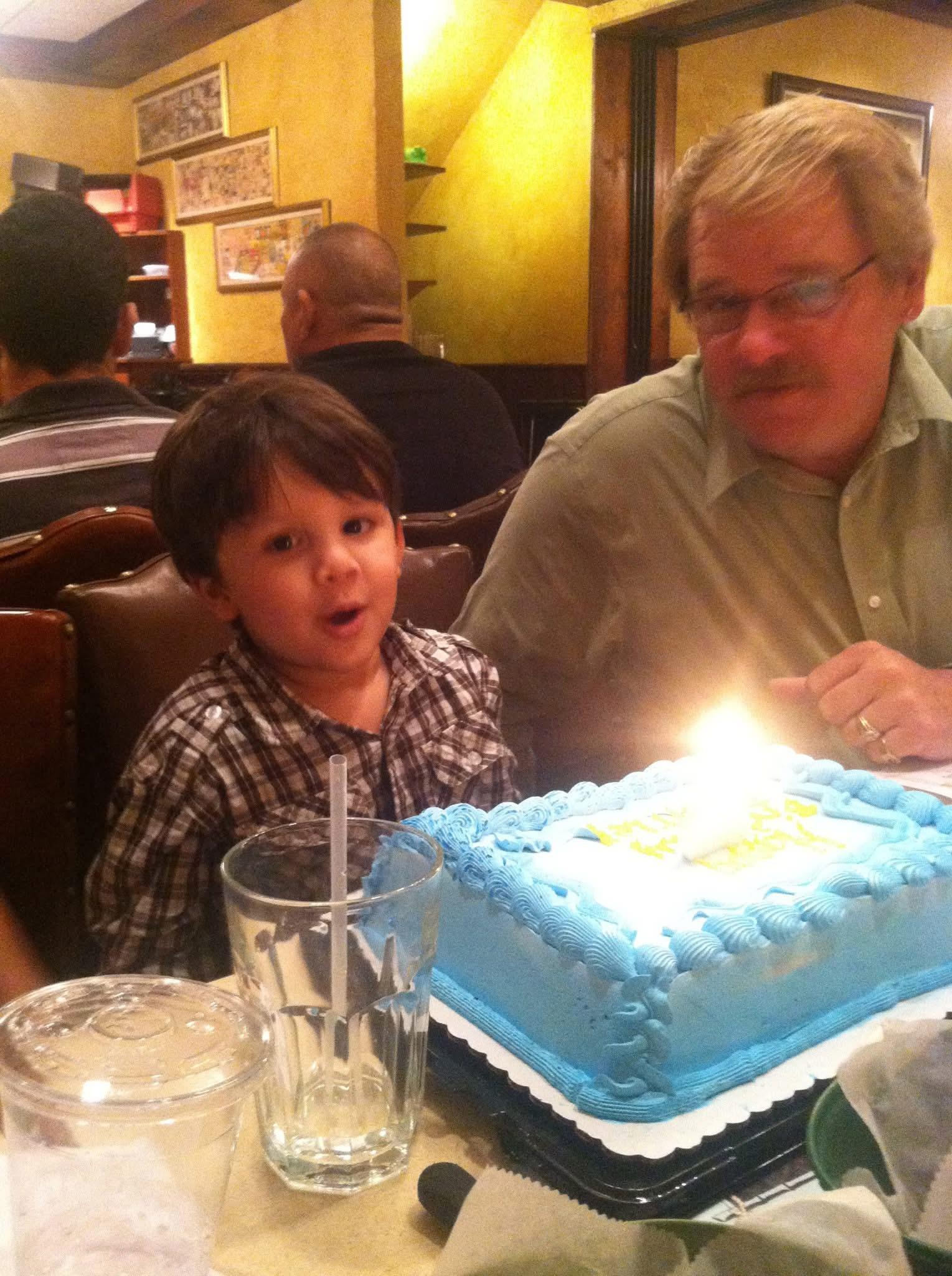 A boy sitting in front of a birthday cake