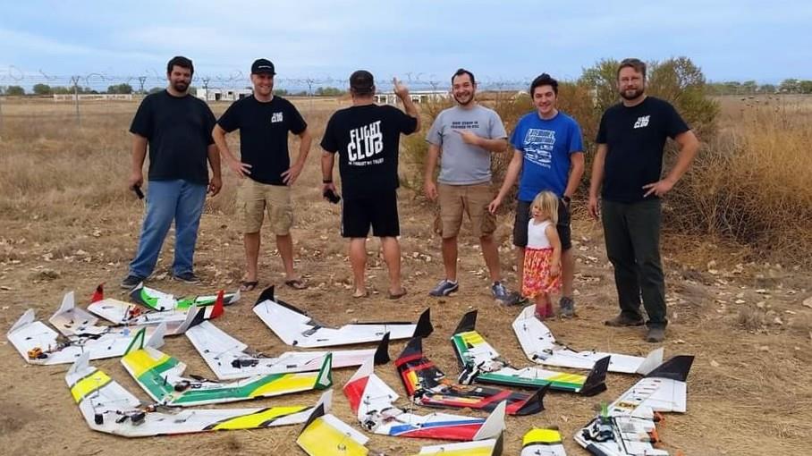 A group of people standing in a field with a group of rc planes
