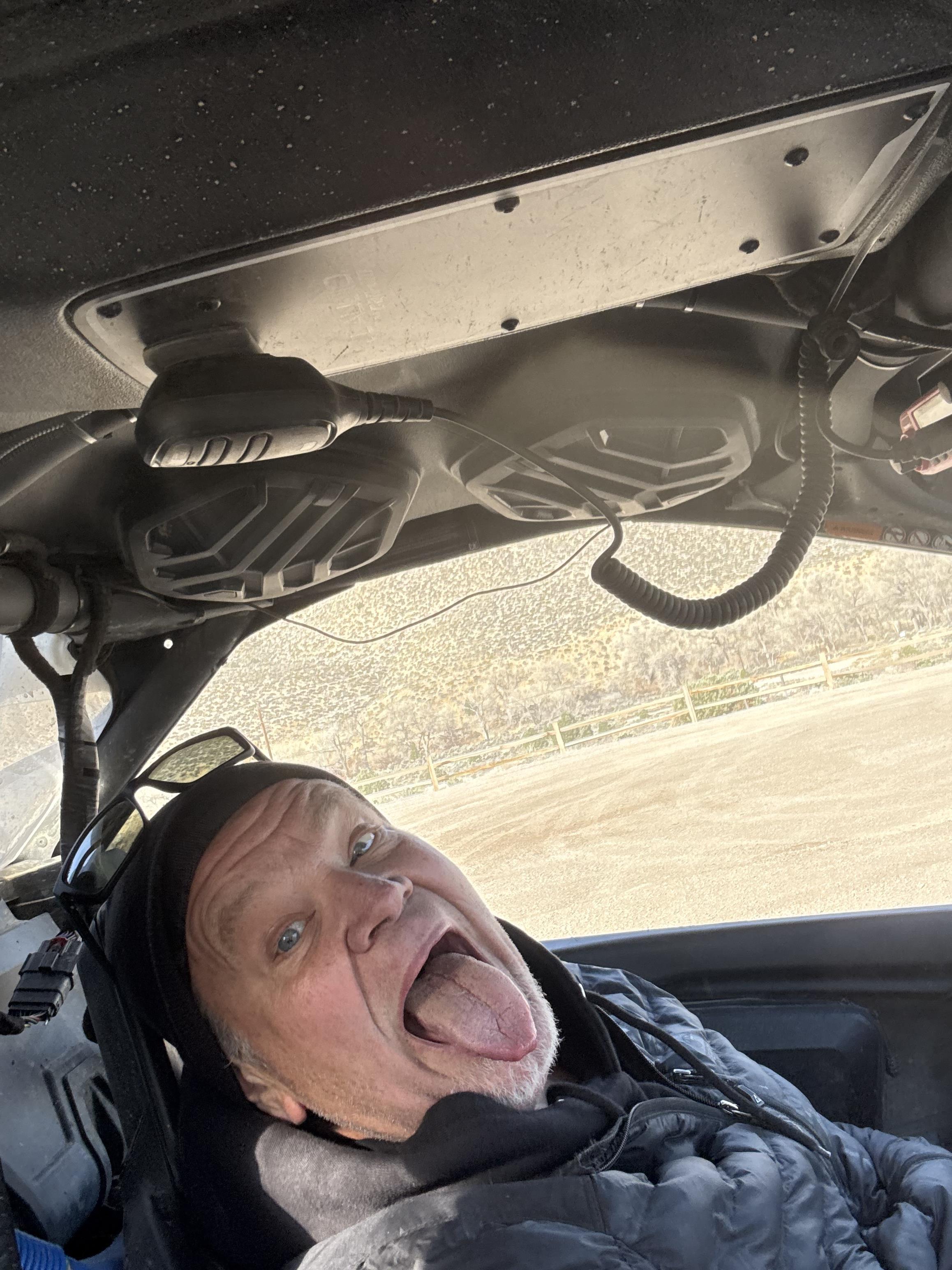 A man sticking his tongue out in a car