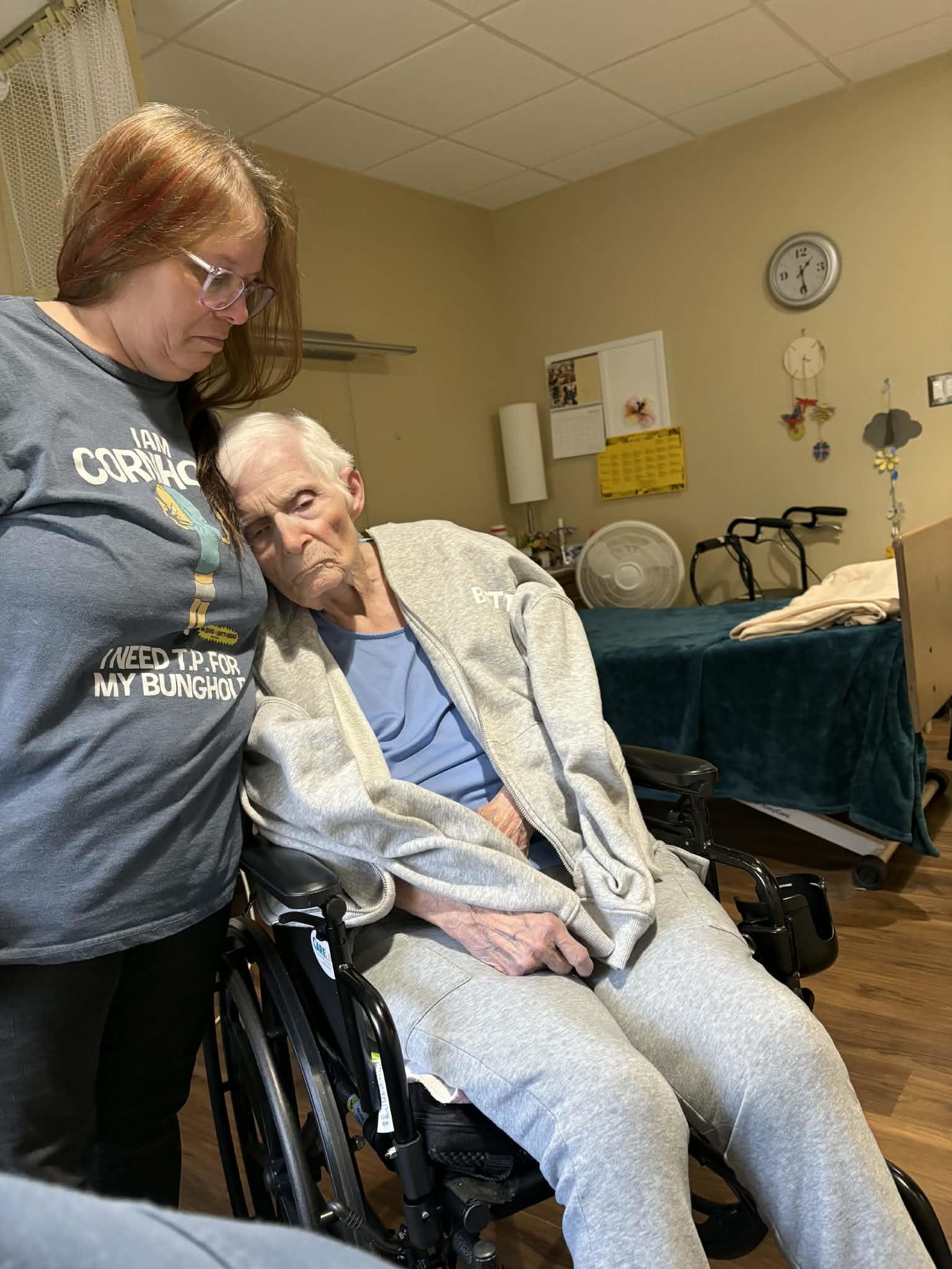 A woman standing next to an elderly woman in a wheelchair