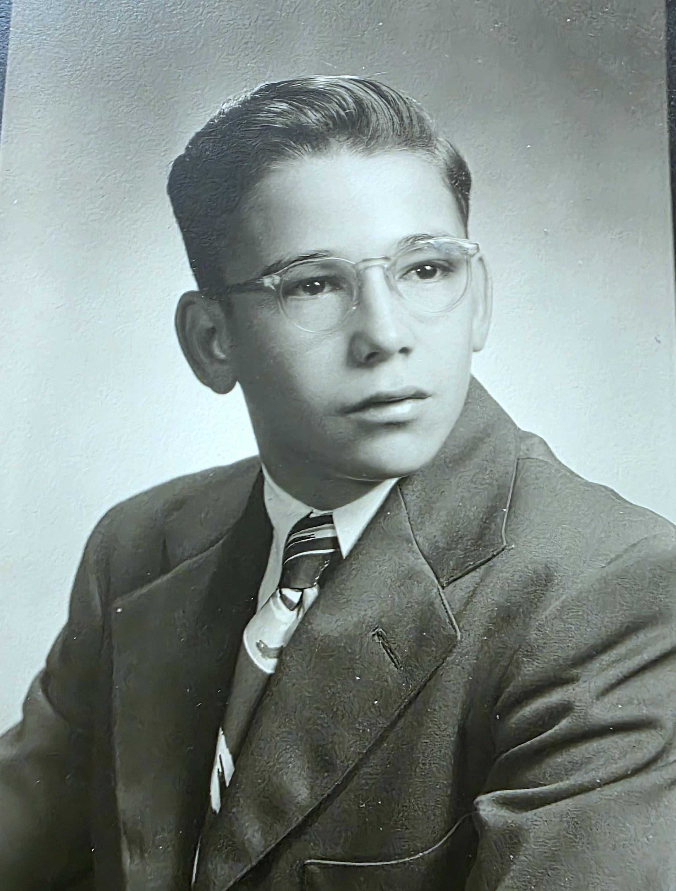 A young man wearing glasses and a suit