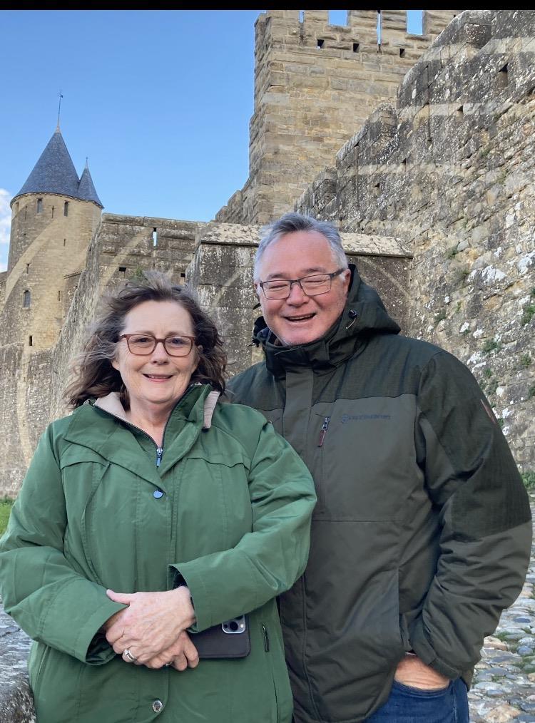 A man and woman standing in front of a stone castle