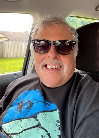A man wearing sunglasses and smiling