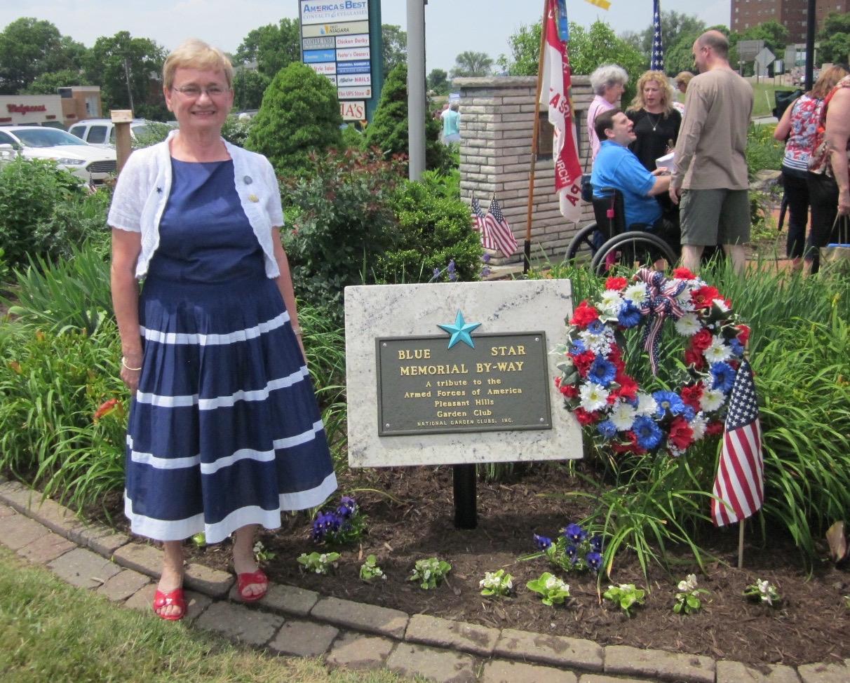 A woman standing in front of a memorial sign