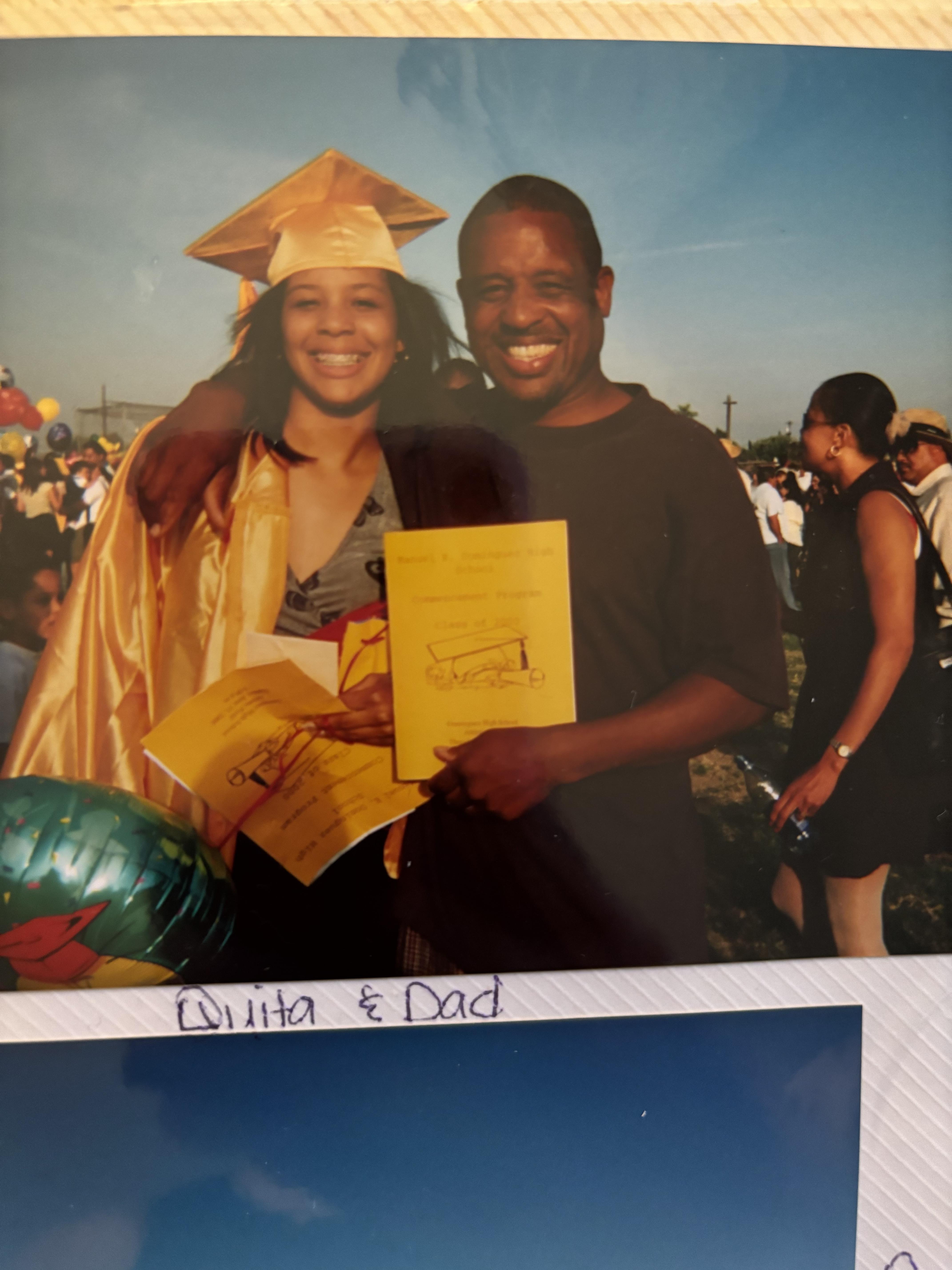 A man and woman in graduation gowns and cap and gown holding papers