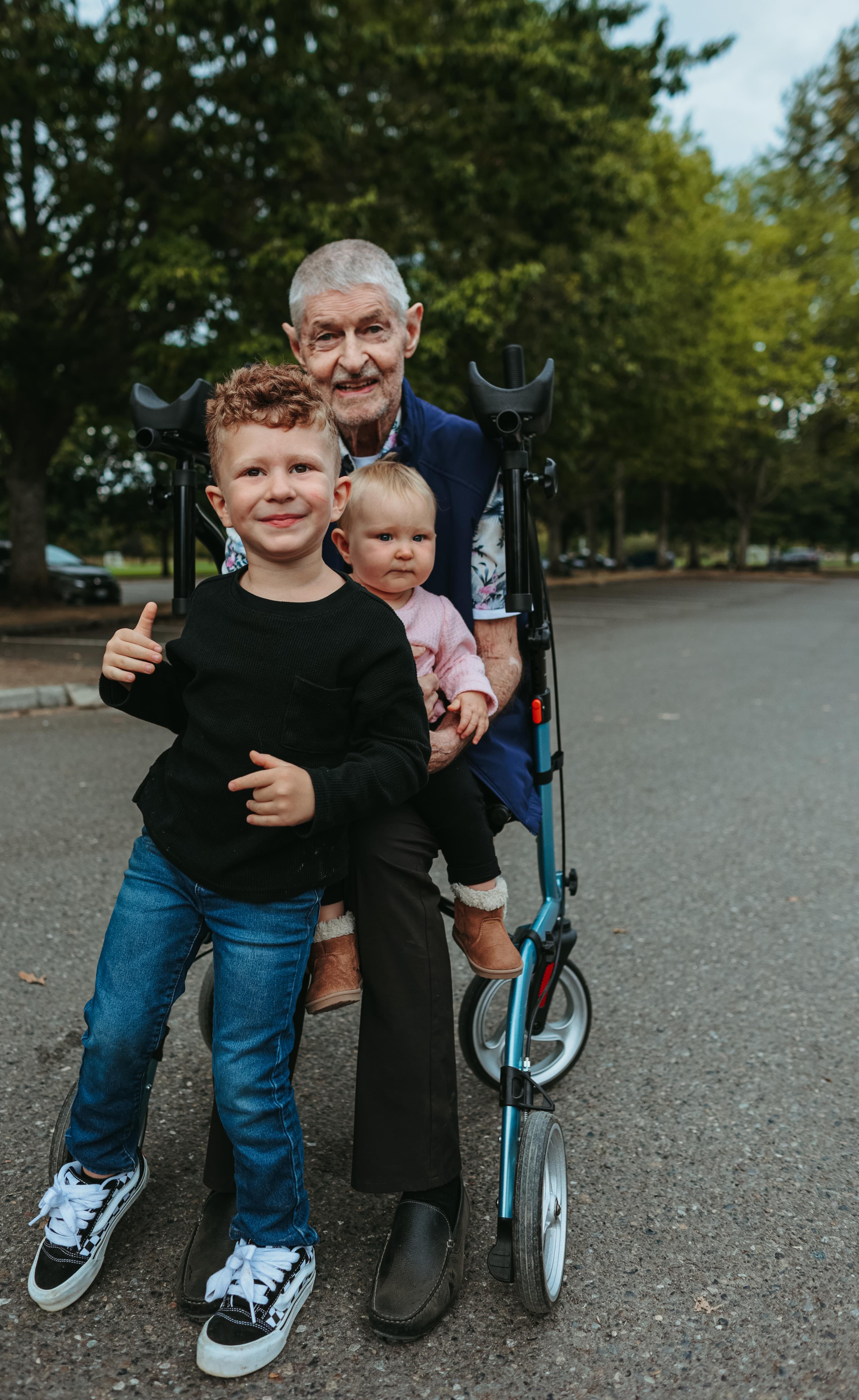 An old man holding a child and a scooter