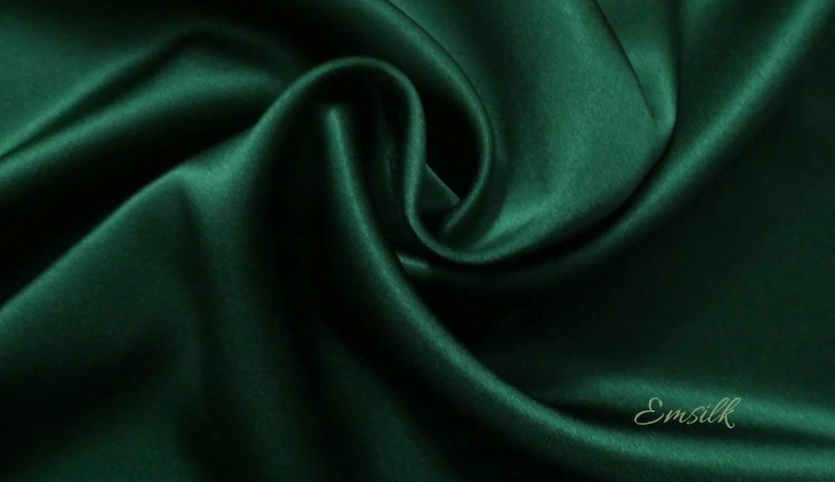 A green satin fabric with a wavy folds