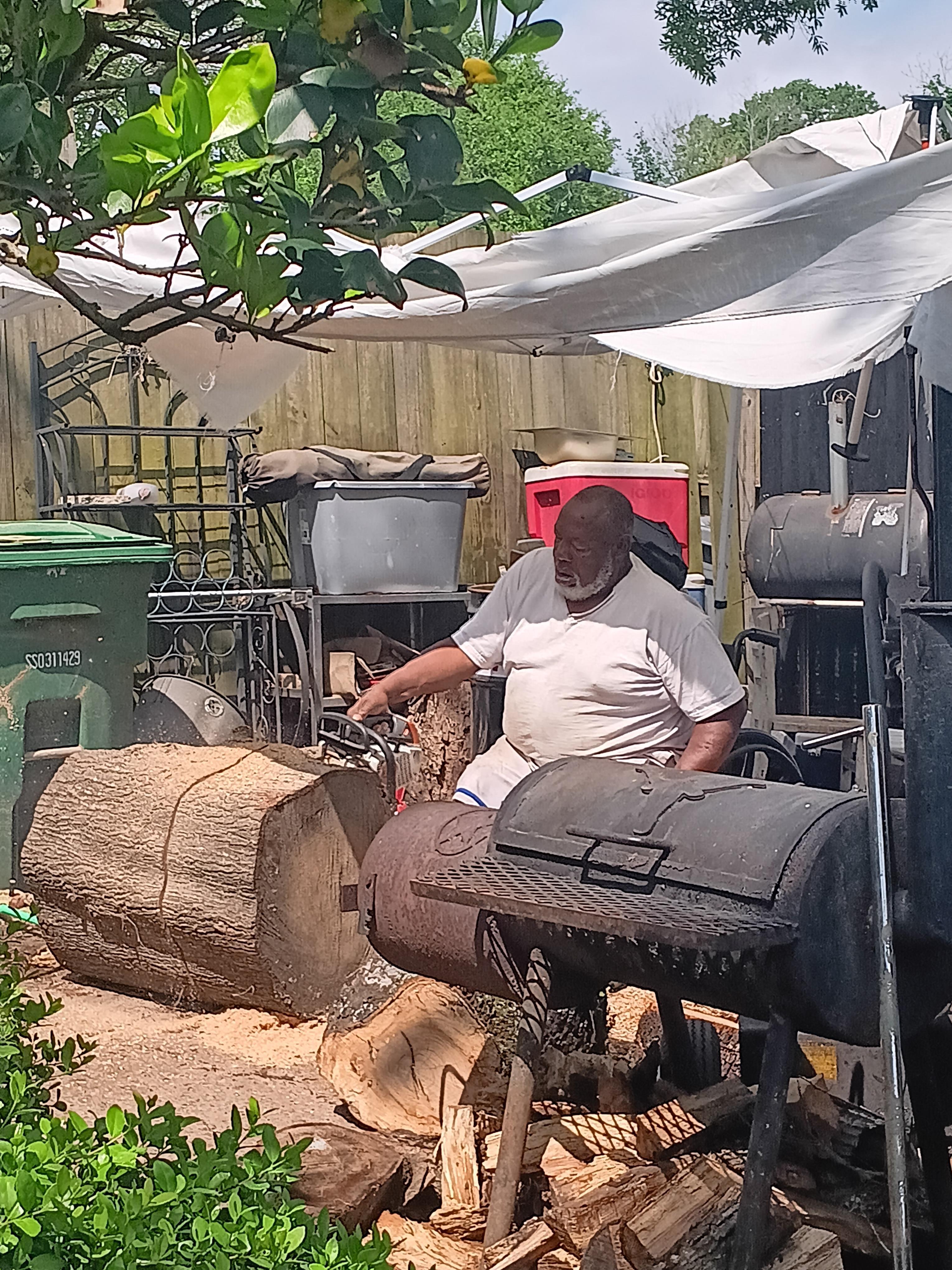 A man sitting on a chair by a large log