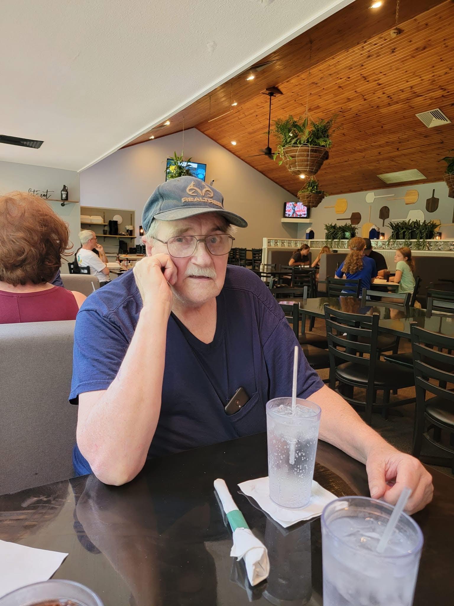 A man sitting at a table with a drink and a phone