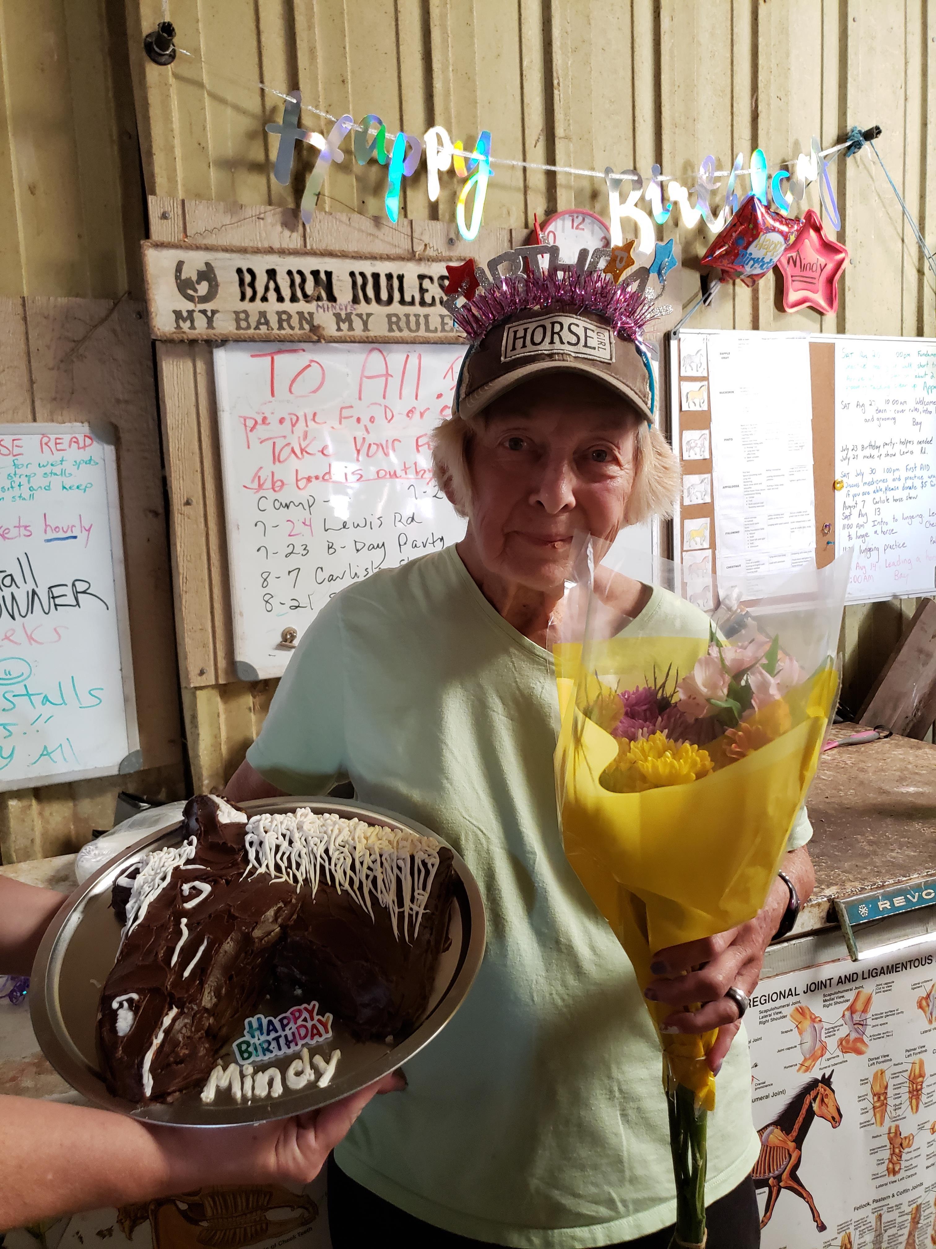 A woman holding a bouquet of flowers and a cake