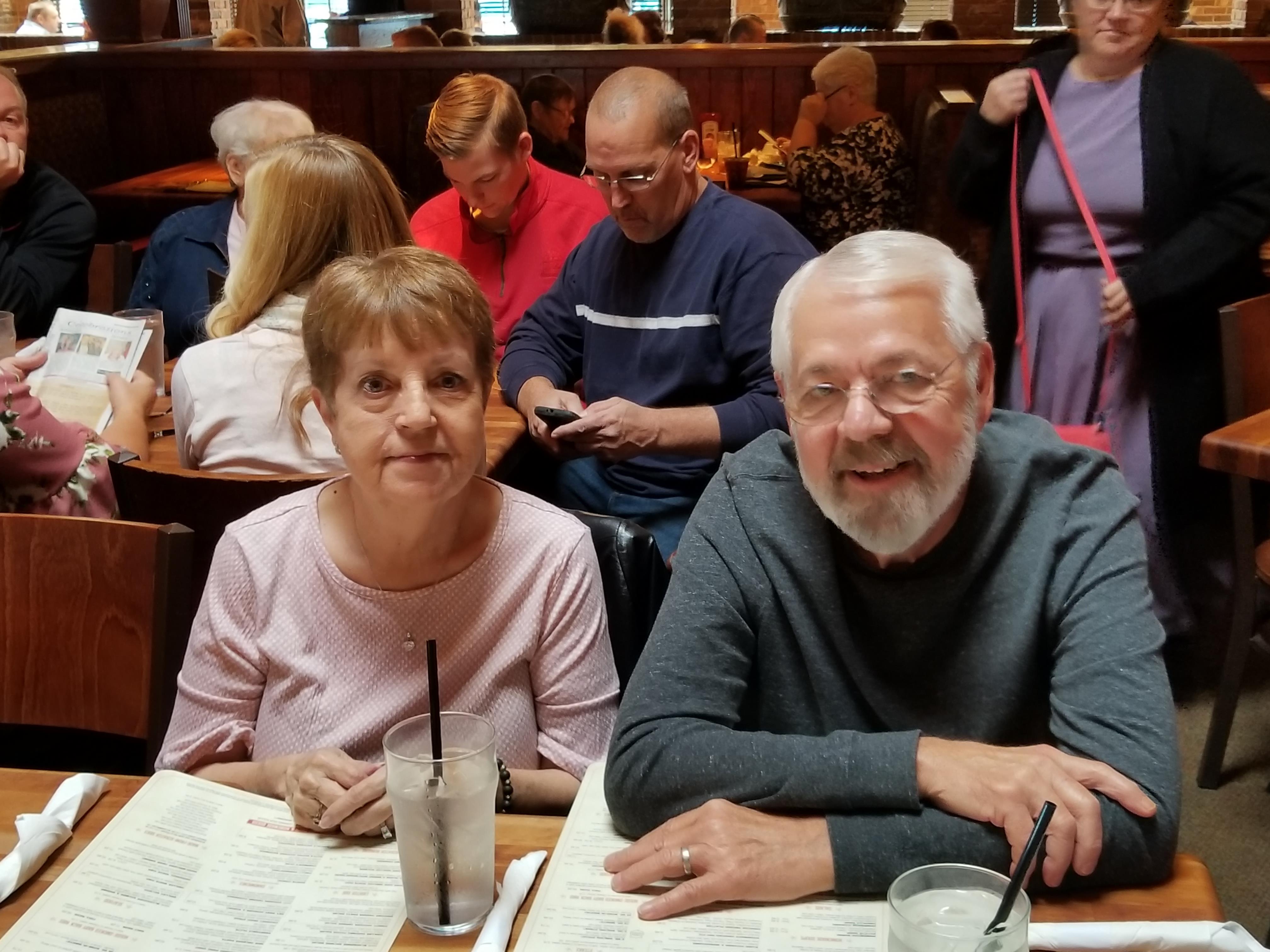 A man and woman sitting at a table with menus