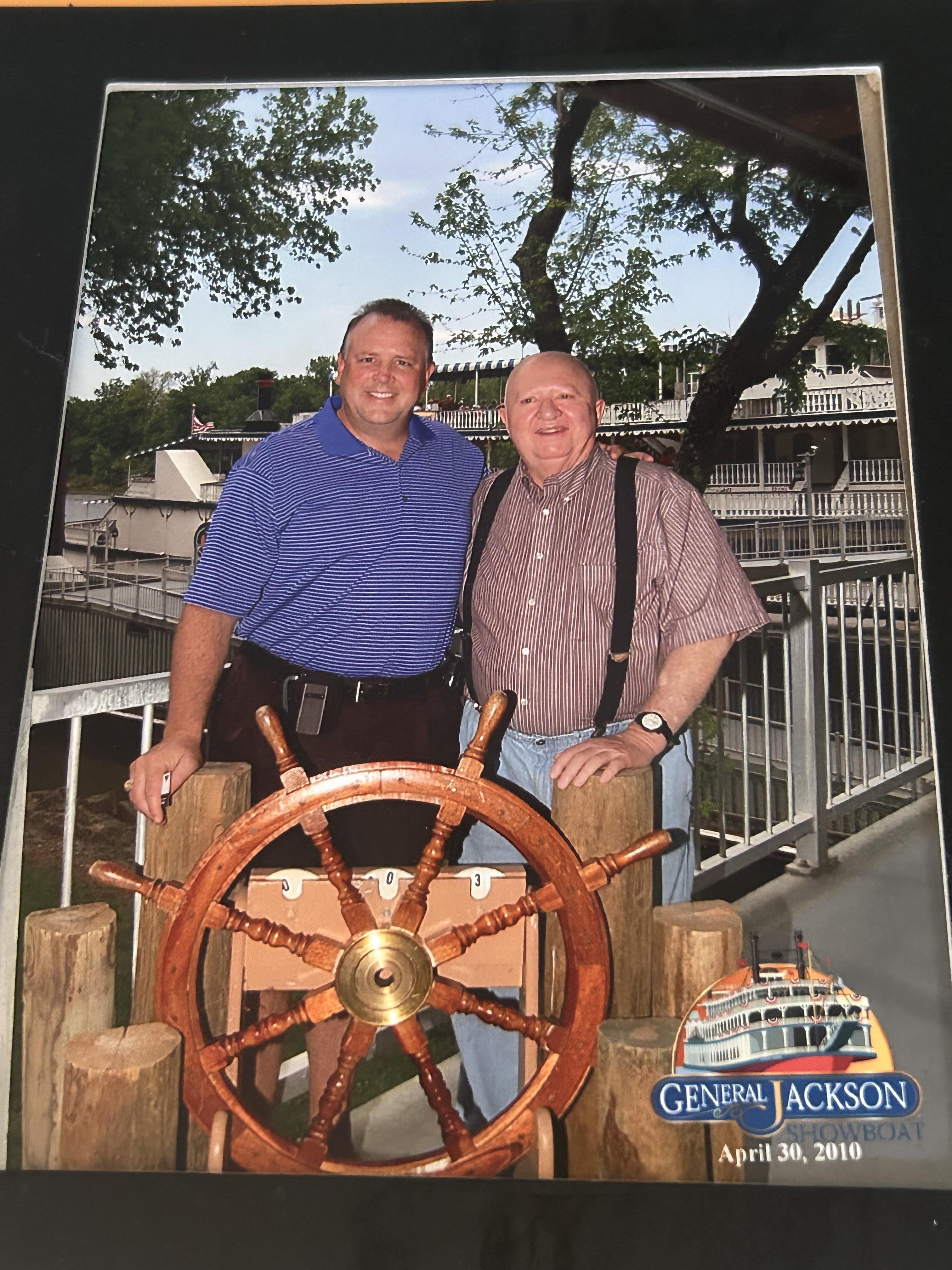 Two men standing next to a steering wheel