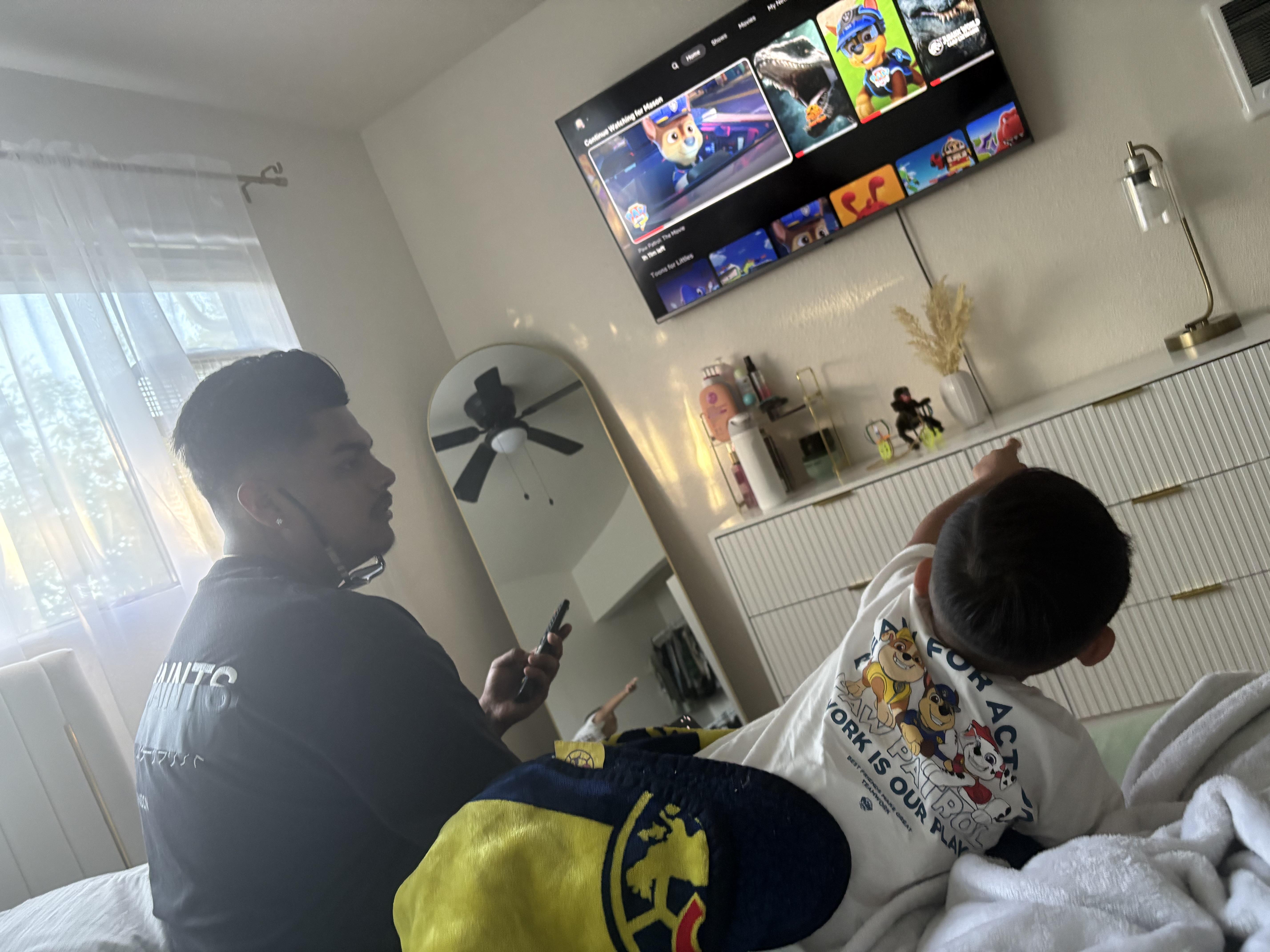 A man sitting in a bed with a boy in a room with a television