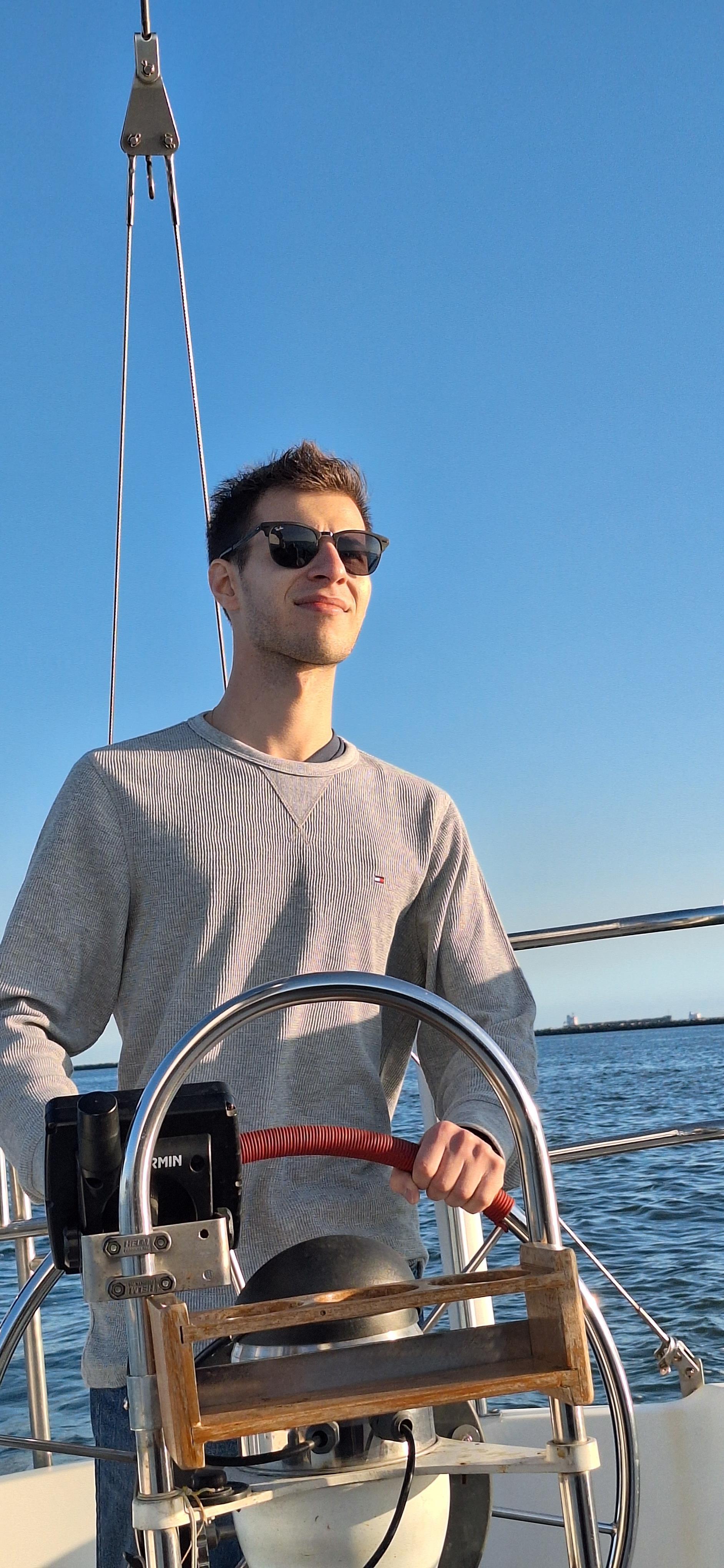 A man wearing sunglasses and standing on a boat