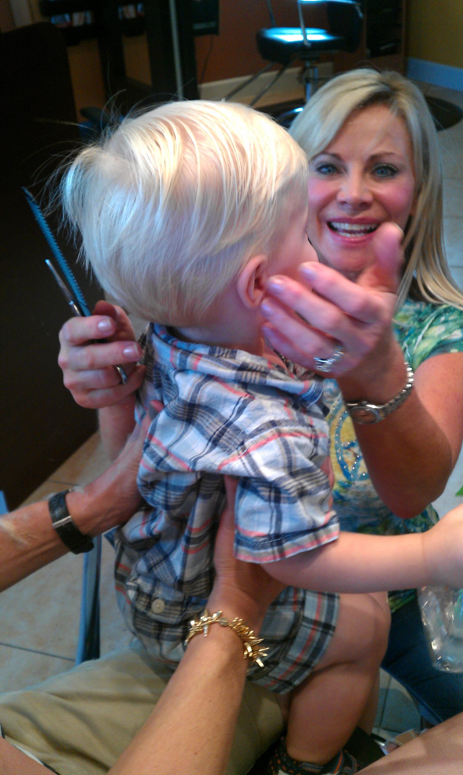 A woman holding a child's haircut