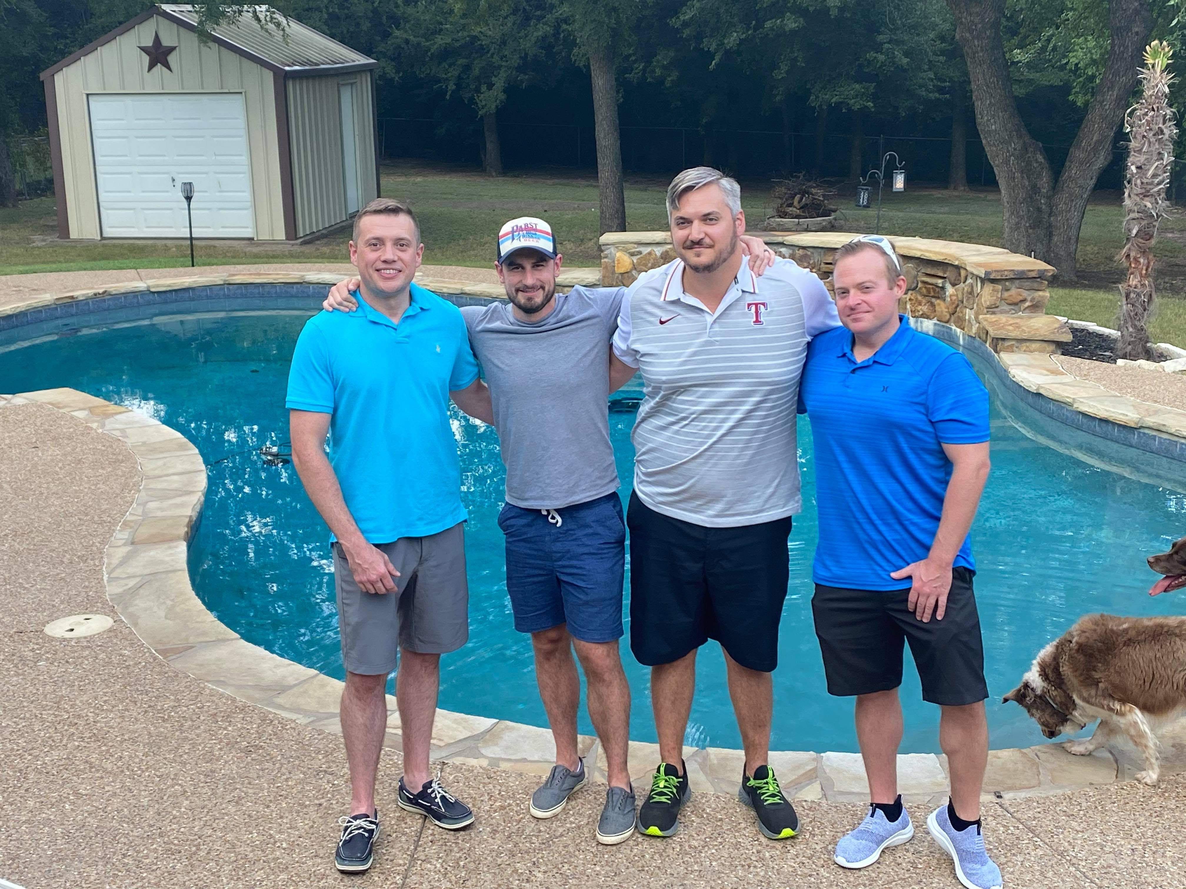 A group of men standing next to a pool