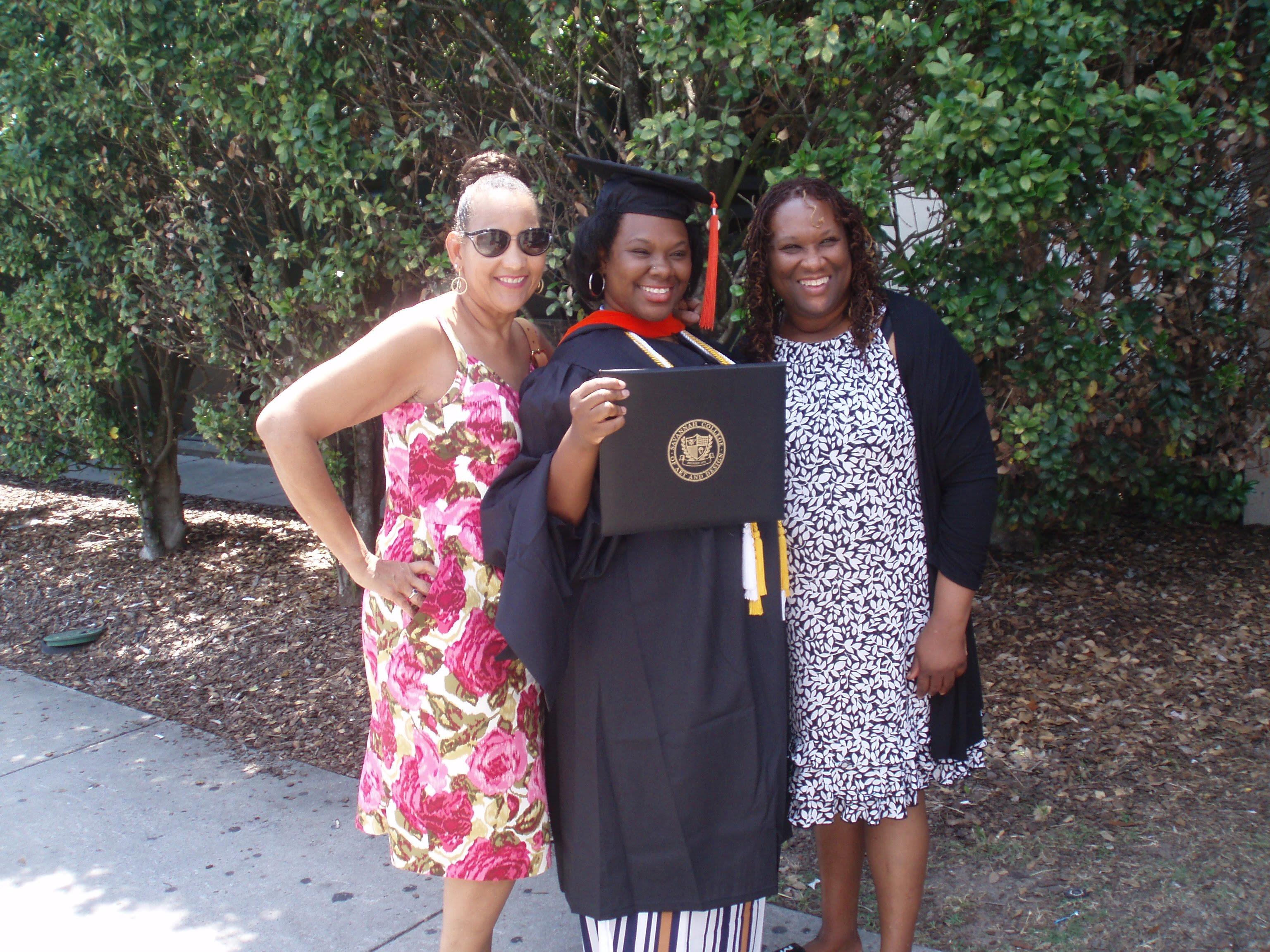 A woman in a graduation gown holding a diploma