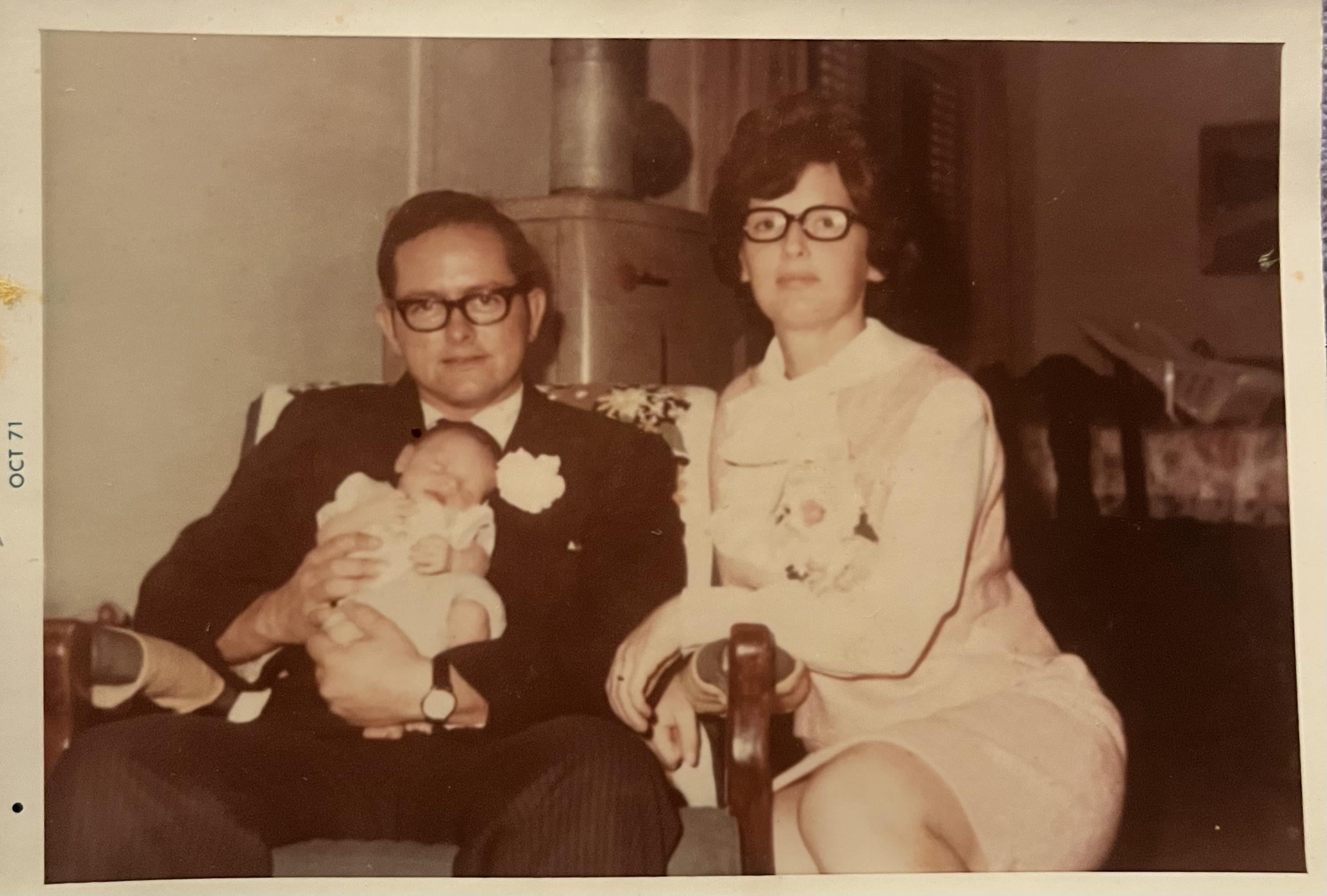 A man and woman sitting in chairs holding a baby
