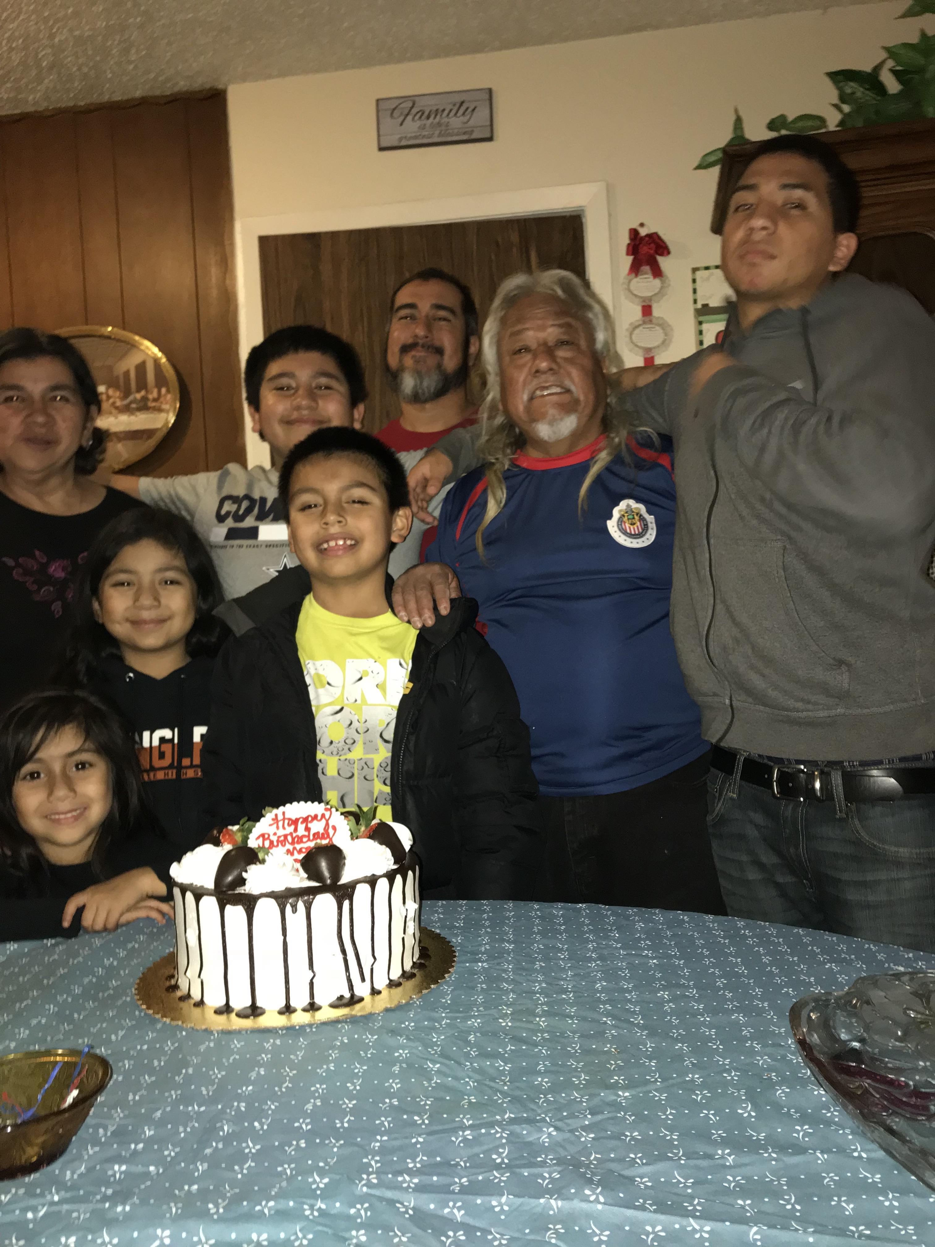 A group of people standing around a cake