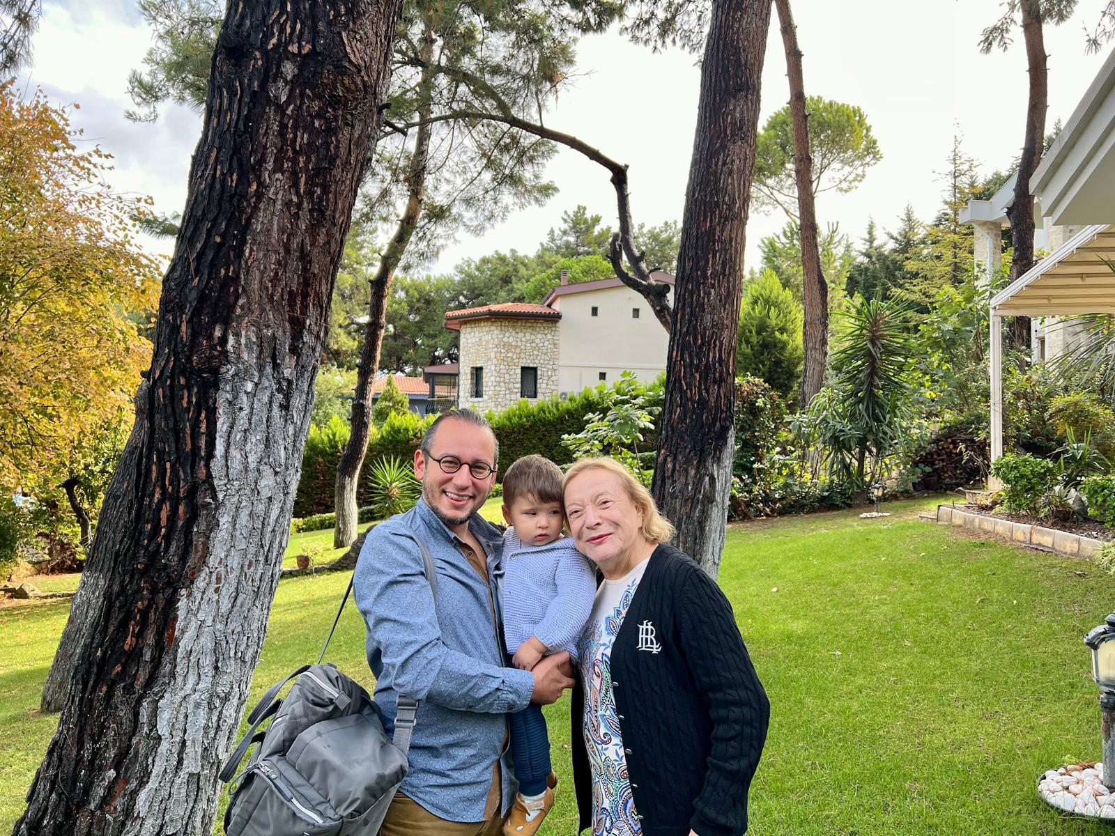 A man and woman with a child standing in front of a tree