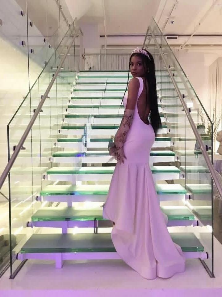 A woman in a white dress and crown standing on a glass staircase