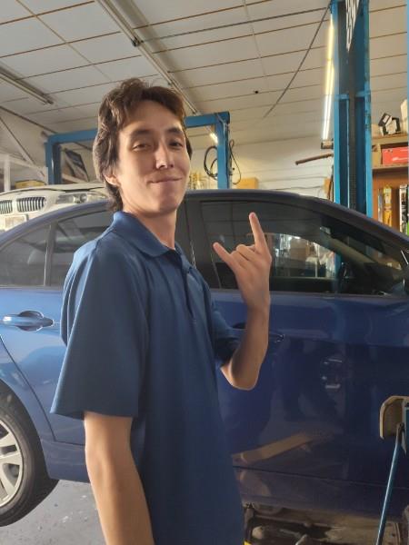 A man in a garage holding up his hand