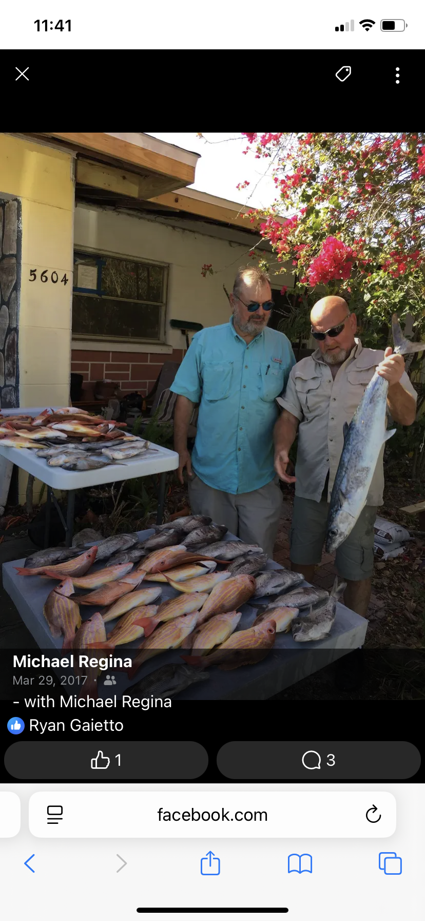 Two men standing next to a table of fish