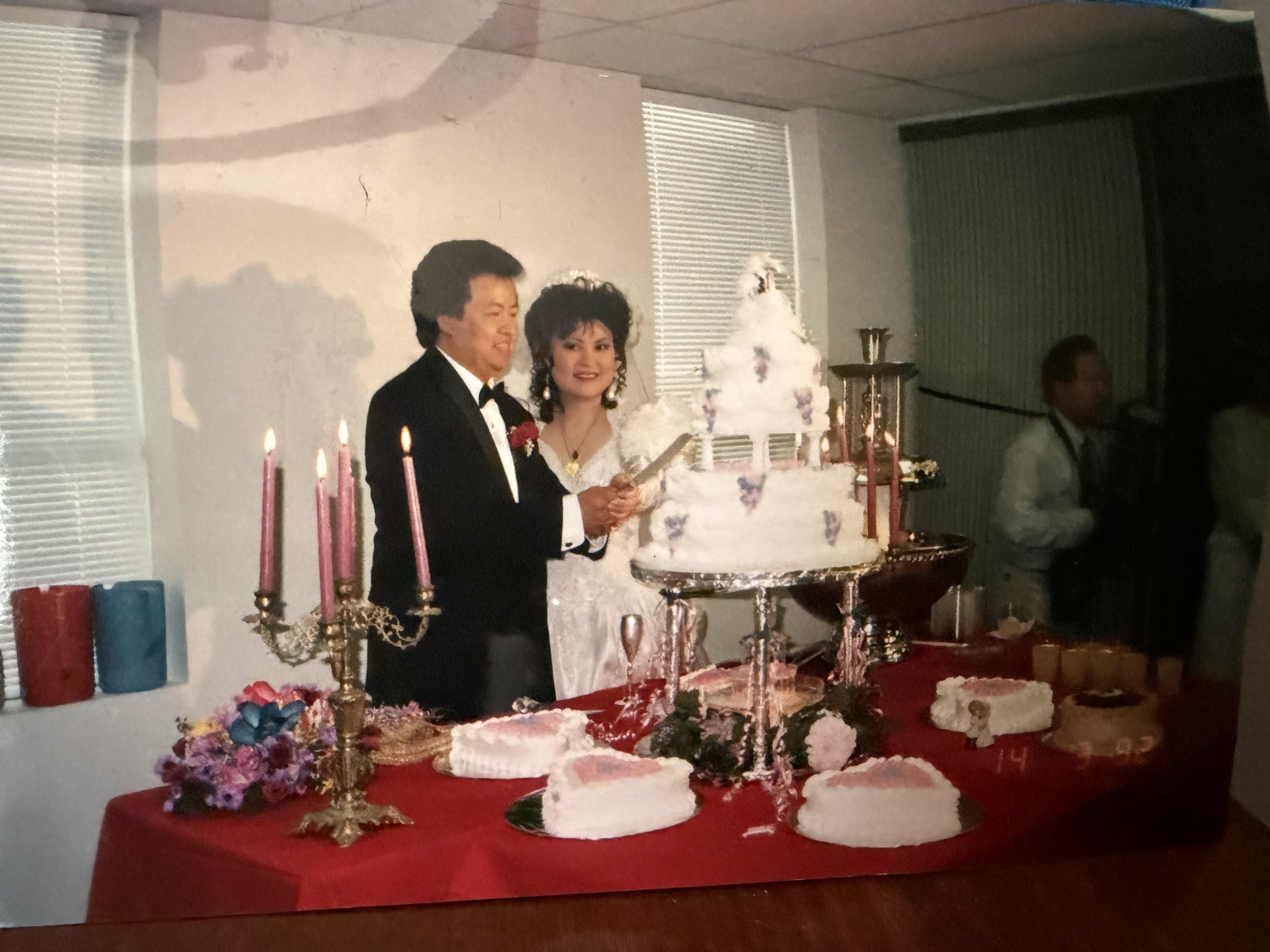 A man and woman standing next to a cake