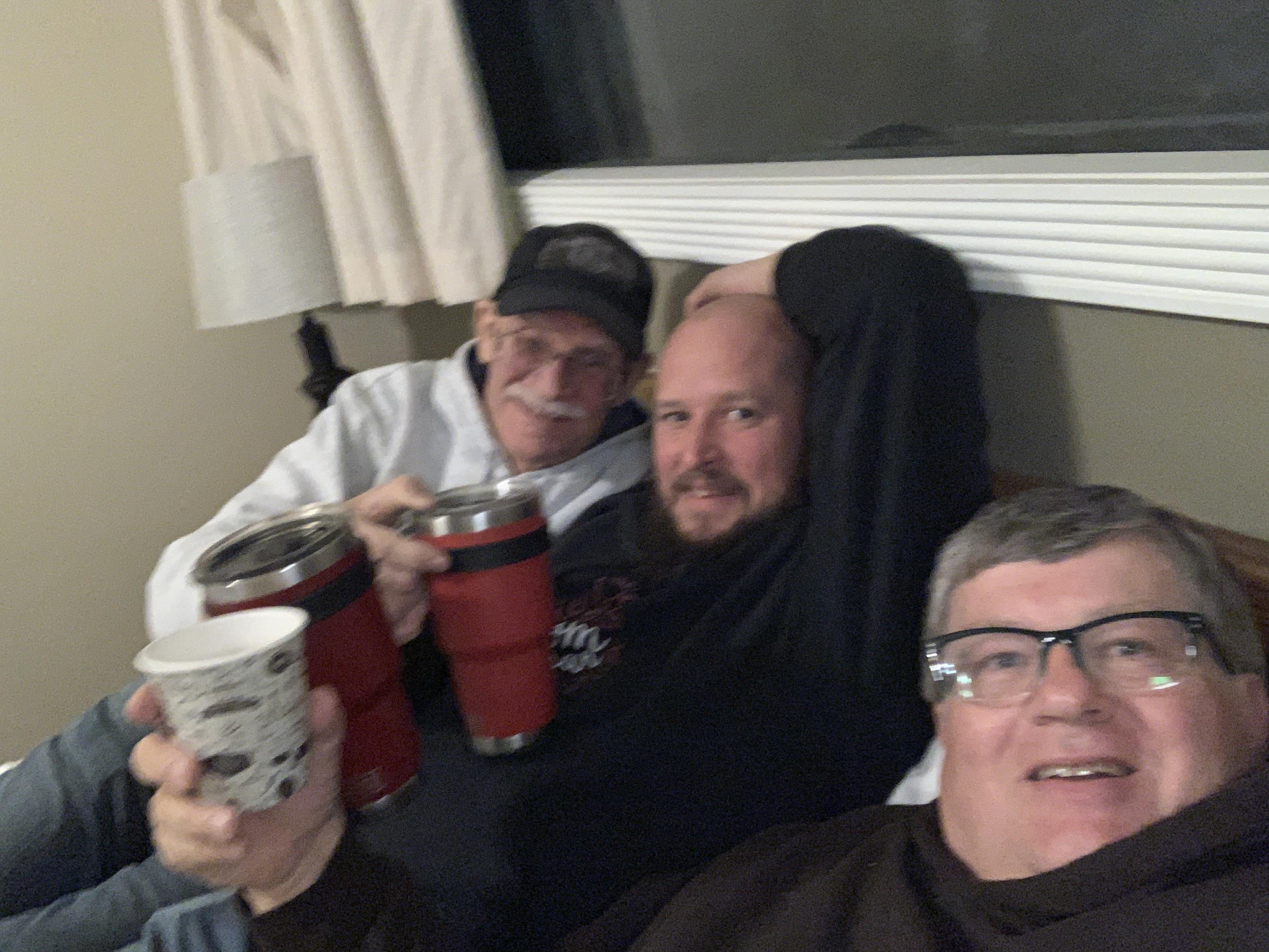 A group of men sitting on a couch holding cups