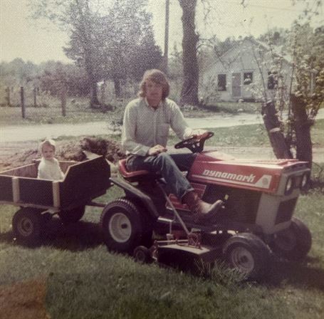 A man riding a tractor with a child in a wagon