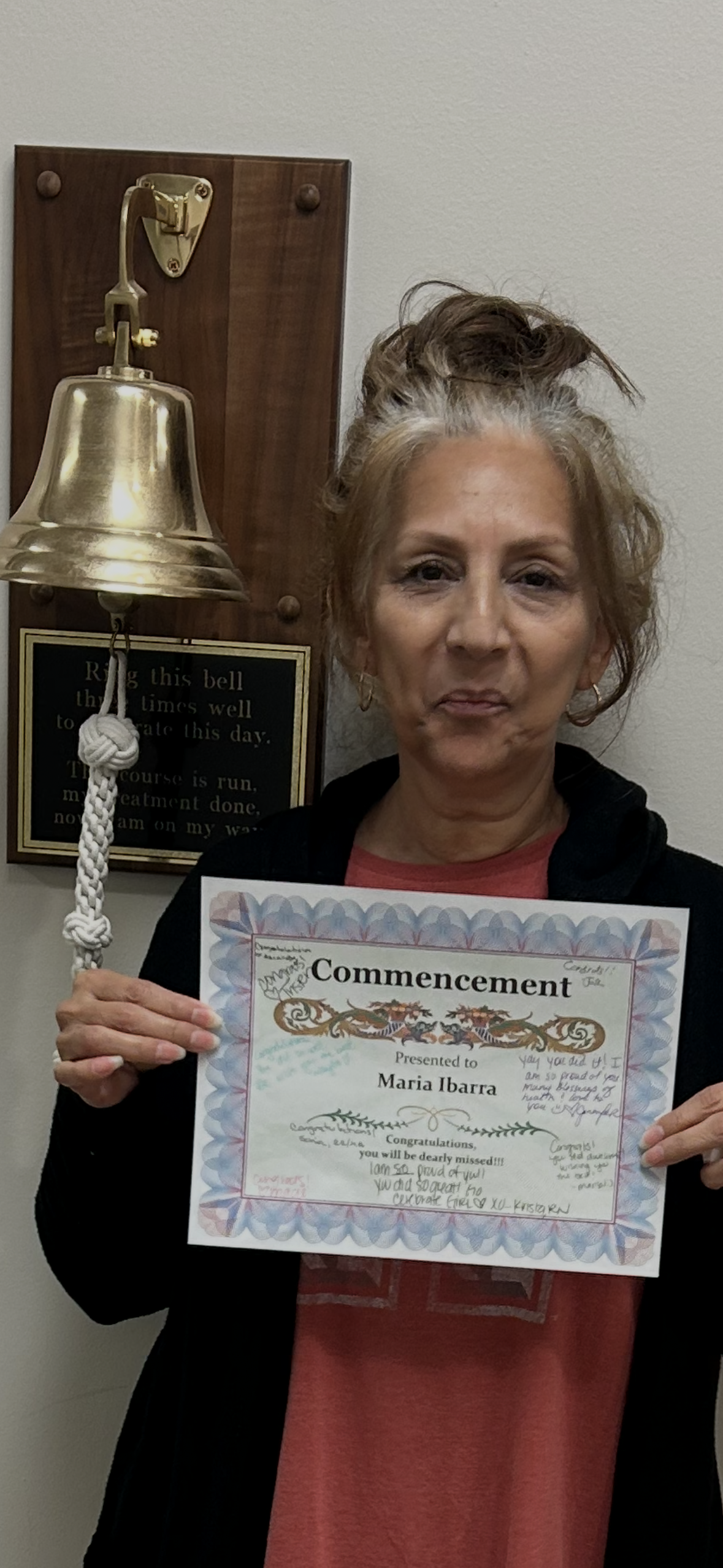 A woman holding a certificate and a bell