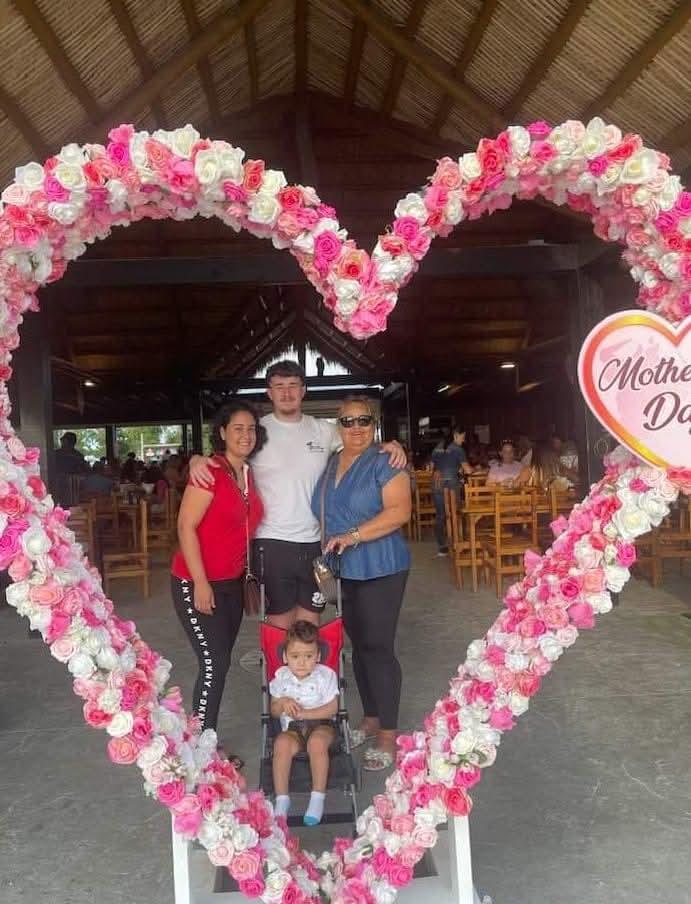A group of people standing in front of a heart shaped flower frame