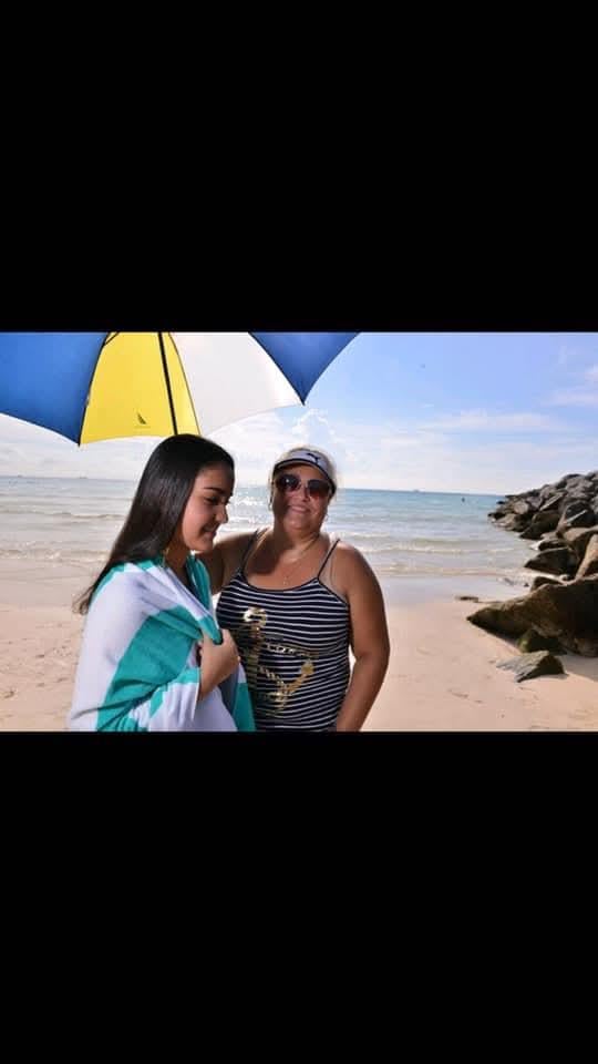 Two women standing on a beach under an umbrella