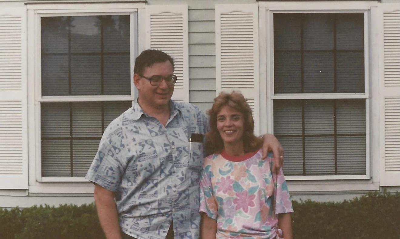 A man and woman standing in front of a house