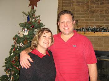 A man and woman standing in front of a christmas tree