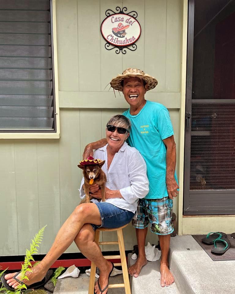 A man and woman sitting on a stool with a dog