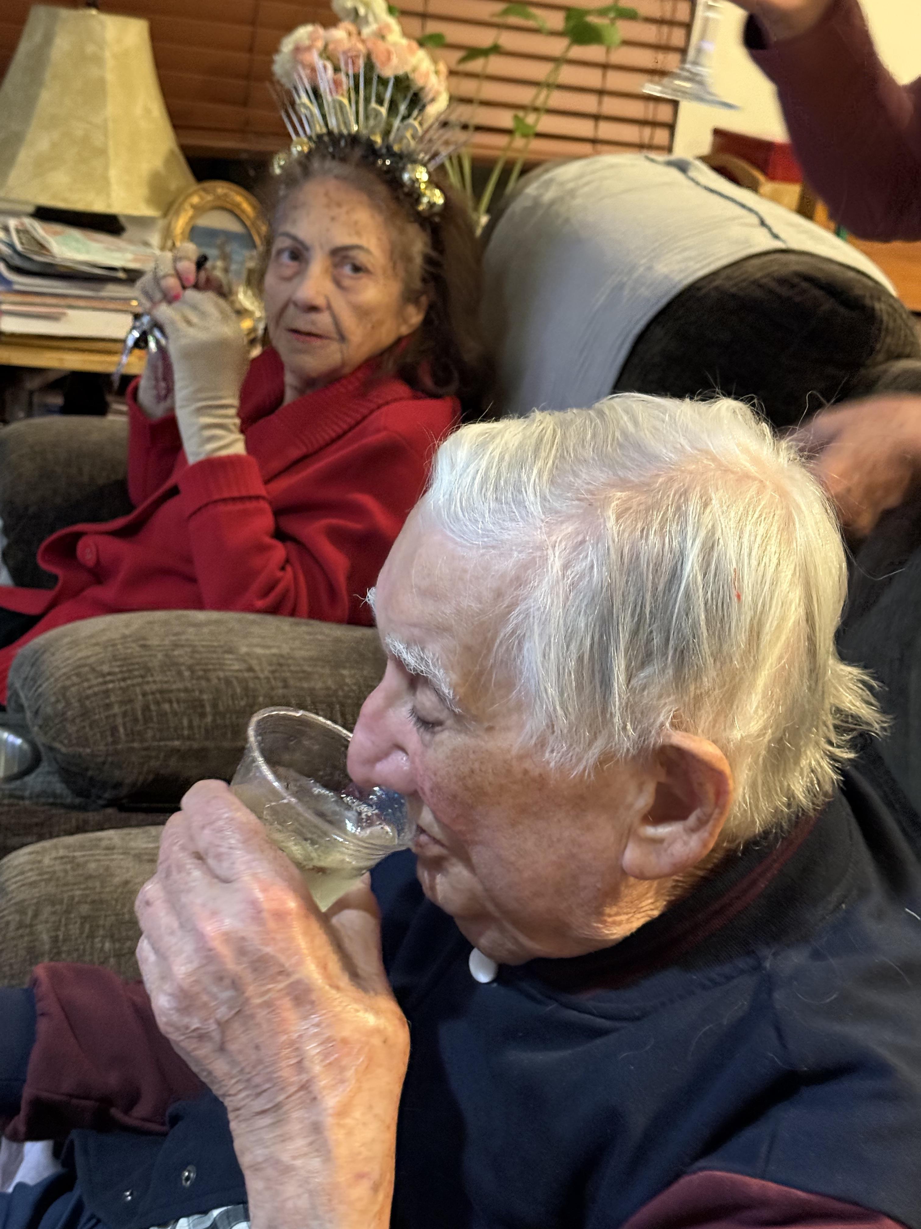 A man and woman sitting on a couch drinking from a glass
