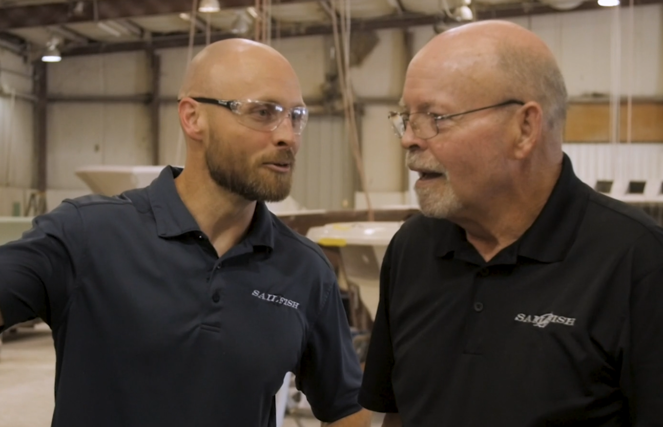 Two men wearing safety glasses and black polo shirts