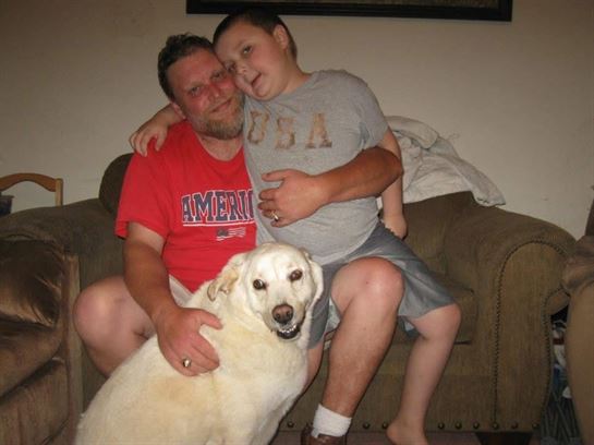 A man and boy sitting on a couch with a dog