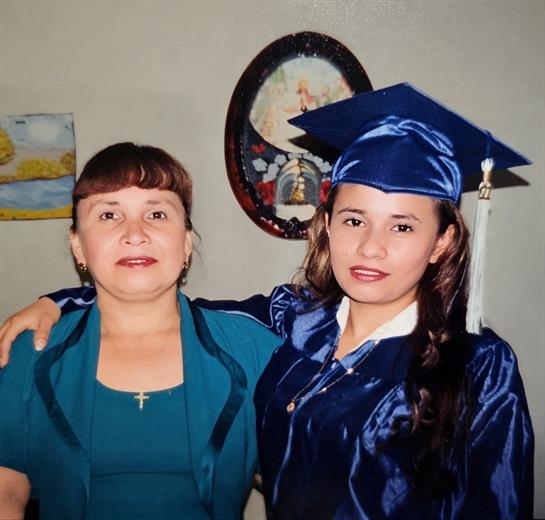 A woman in a blue gown and cap posing with a woman in a blue gown