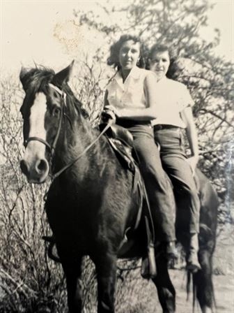 Two women sitting on a horse