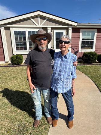 A man and woman standing in front of a house